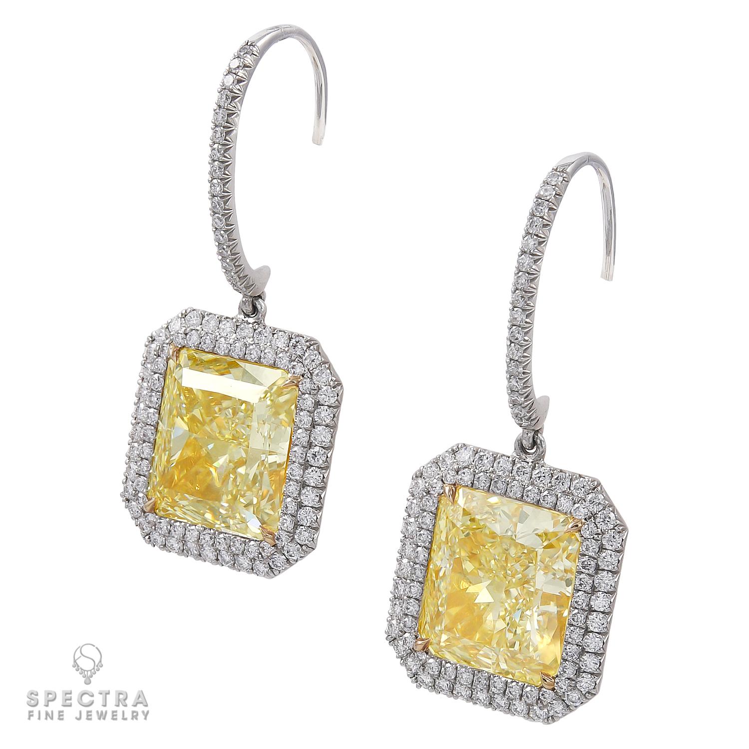 These elegant Diamond Halo Drop Earrings made by Spectra Fine Jewelry in the 21st century, circa 2010, showcase two radiant-cut diamonds set in warm 18k yellow gold each with 4 talon prongs. The diamonds are estimated as 7.01 carats of Y color and