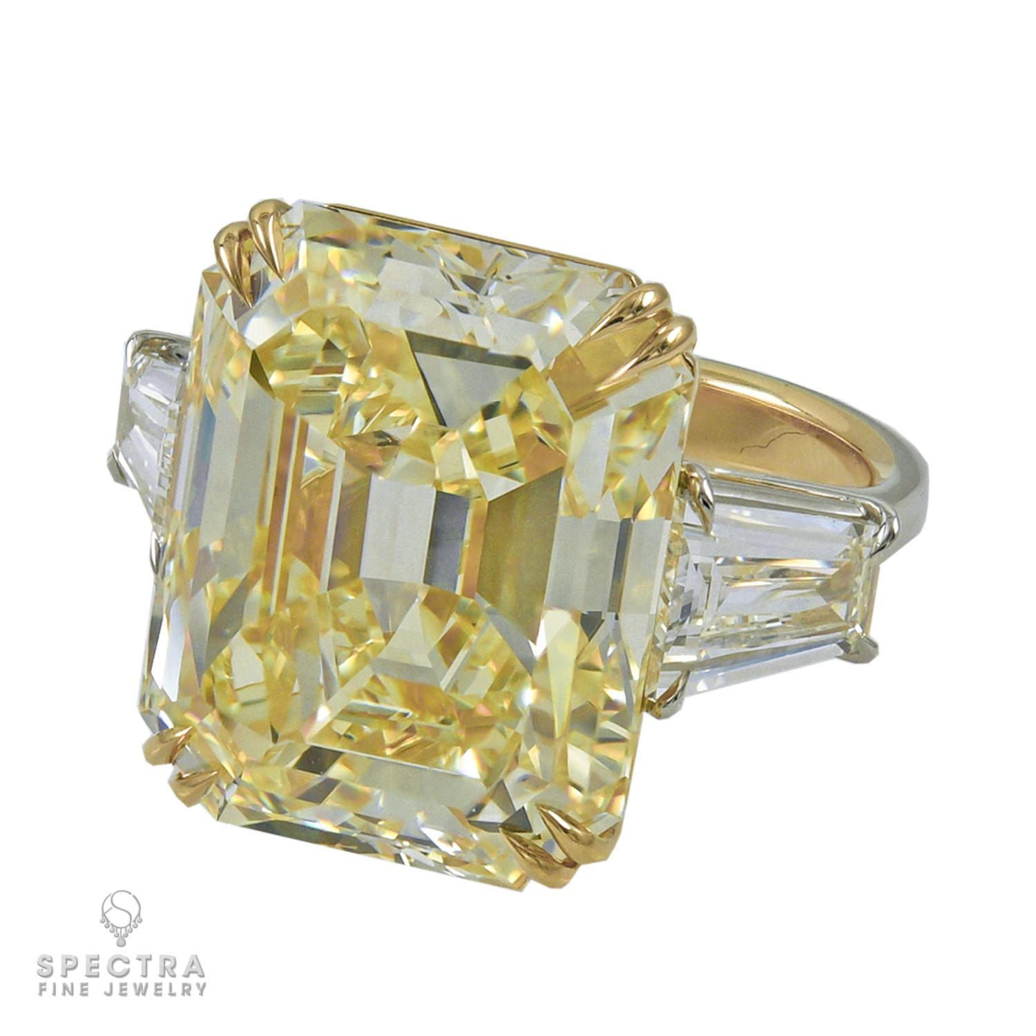 This Art Deco-inspired platinum and 18K gold ring made by Spectra Fine Jewelry in 2022 is stunning as a cocktail, engagement, or celebration ring, featuring a very large emerald-cut fancy yellow diamond, weighing approximately 23.16 carats. The