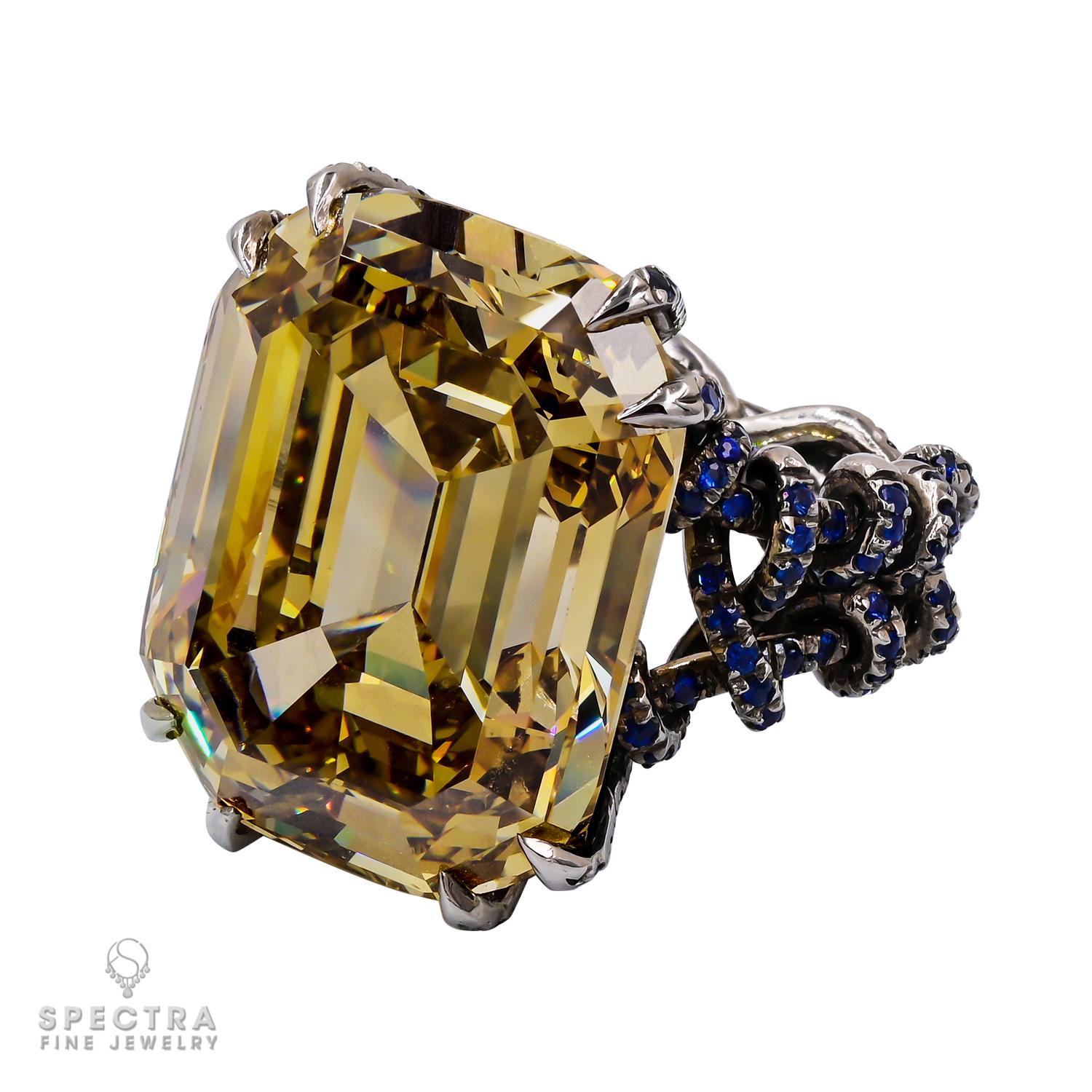 Un anello solitario tradizionalmente mette in mostra una sola pietra preziosa di rilievo, ma questo splendido pezzo sfida le convenzioni. Caratterizzato da un raro diamante Fancy marrone scuro-giallo verdastro, il centro è splendidamente accentuato