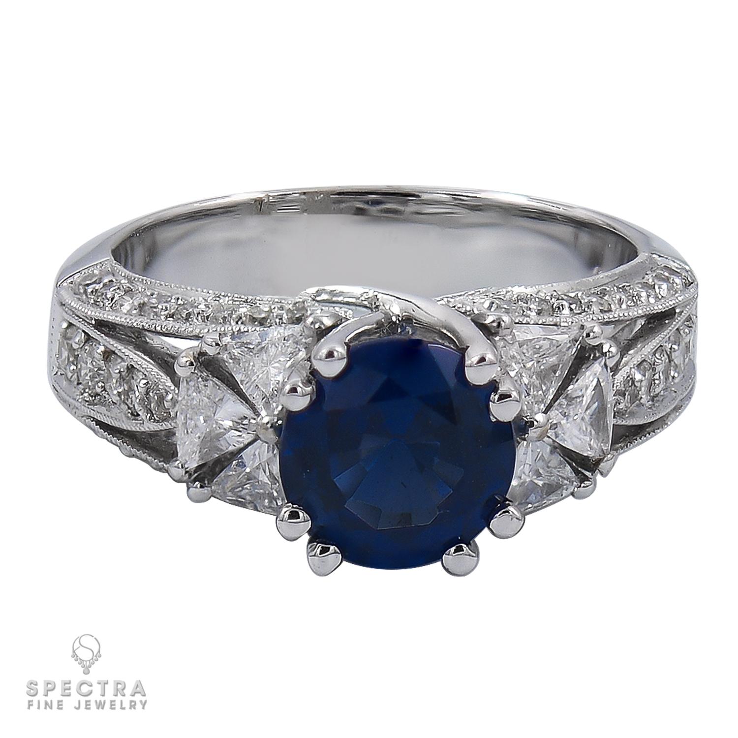 Cette ravissante bague de cocktail en or blanc 18kt met en valeur un saphir bleu rond de 2,01 carats, entouré d'un halo captivant de six diamants blancs taillés en trillion. Le cadre géométrique apporte une touche de modernité au design tout en