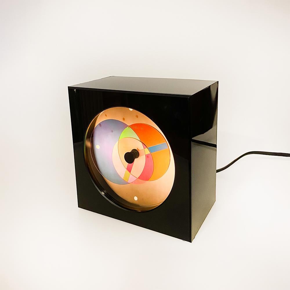 Spectrum Black-Hole desk Clock manufactured by Shimoda Electric, Japan.

It consists of 3 polarizing filters that, turning like needles, change the color. 

Plastic box, has a small crack on the back in one of its closures.

Measurements: 16 x