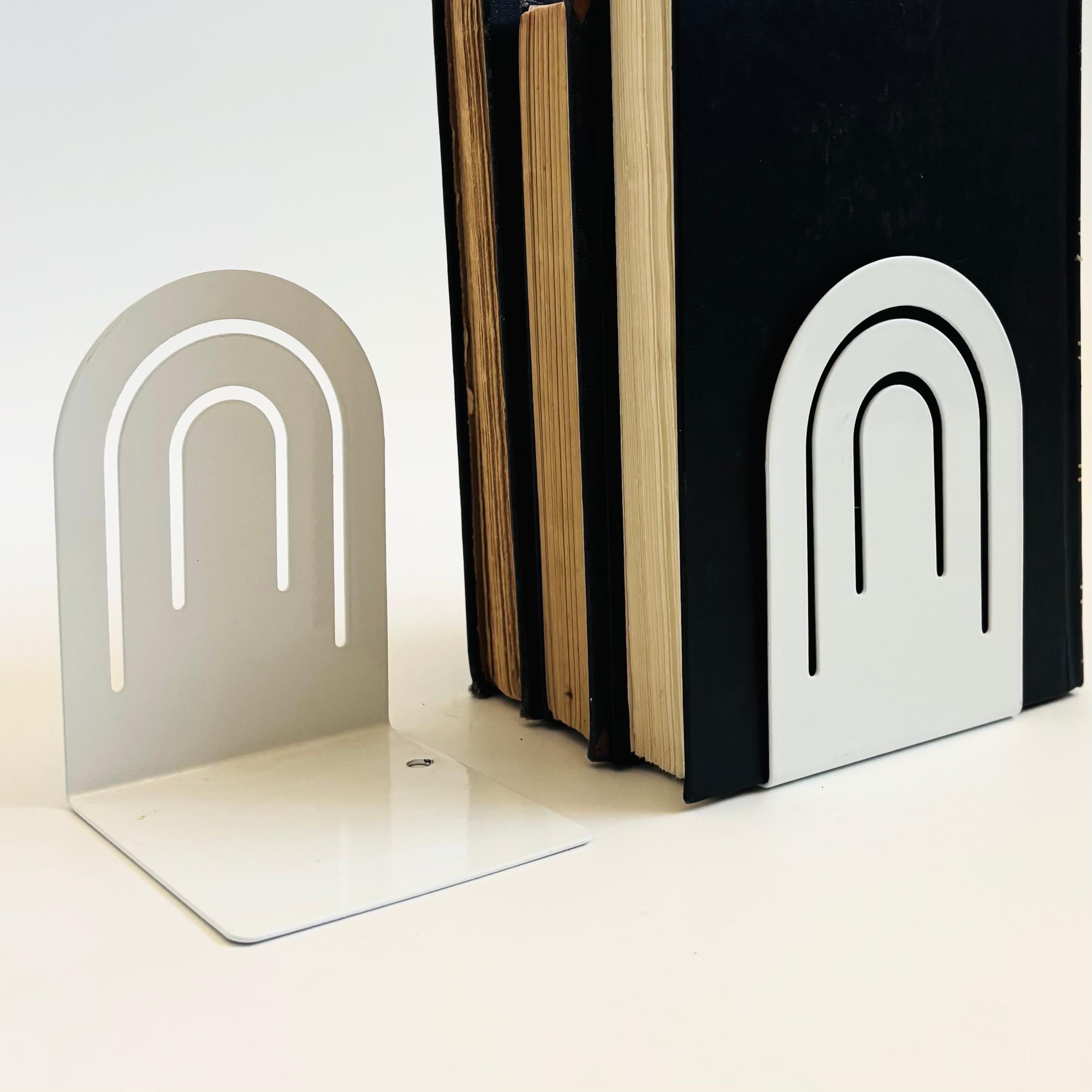 Une paire de serre-livres en métal postmoderne vintage des années 1980. Finition blanc brillant en forme d'arche avec un design de ligne arquée perforée. Fabriqué par Spectrum Designs de Cleveland, OH et légèrement marqué sur la base.

