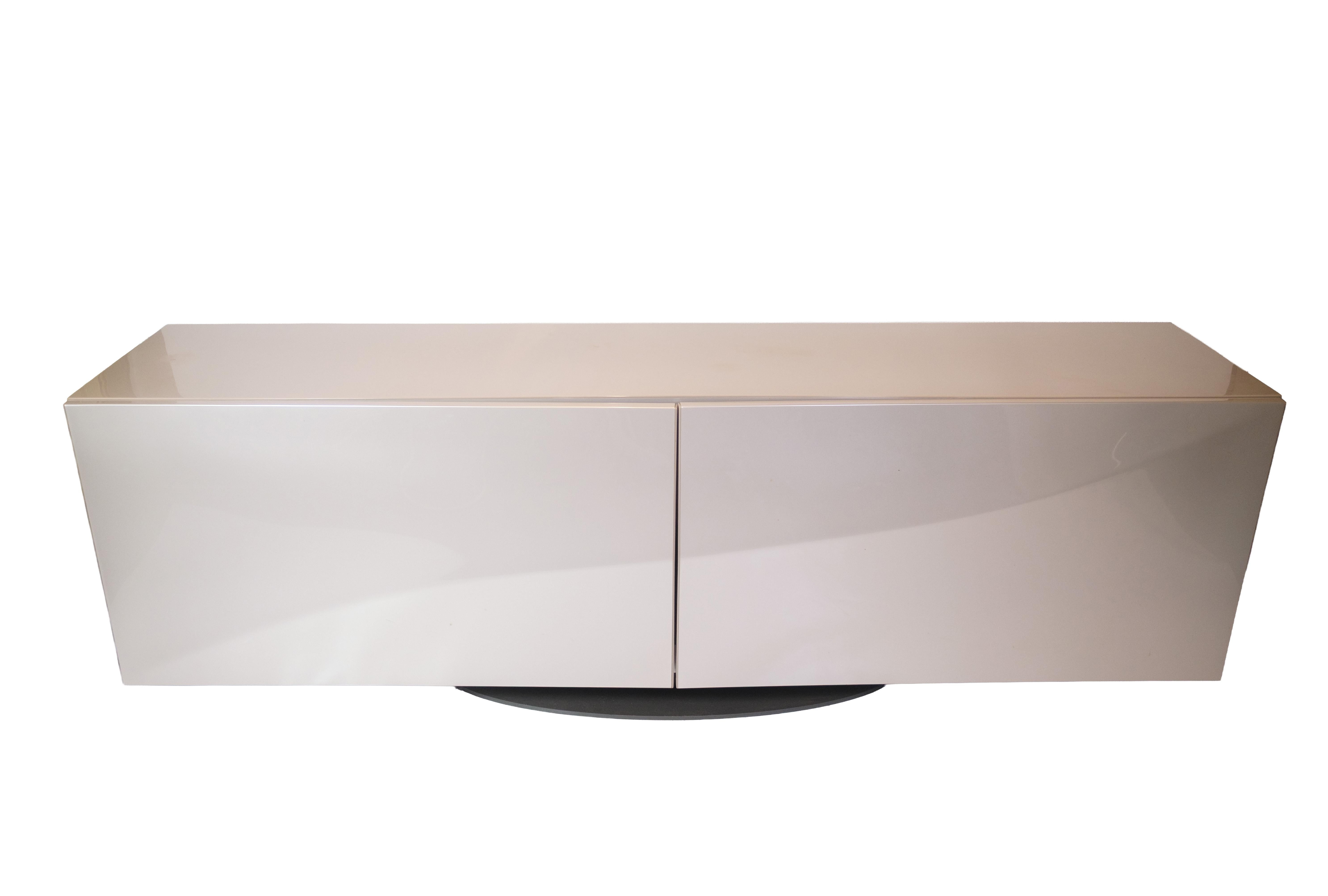 Futuristic sideboard from Roche Bobois Paris, designed by Sacha Lakic. Model Speed ​​Up is made in high-gloss gray with organic curves and sliding doors, placed on a round base in black steel. The floating front surface gives the sideboard an almost