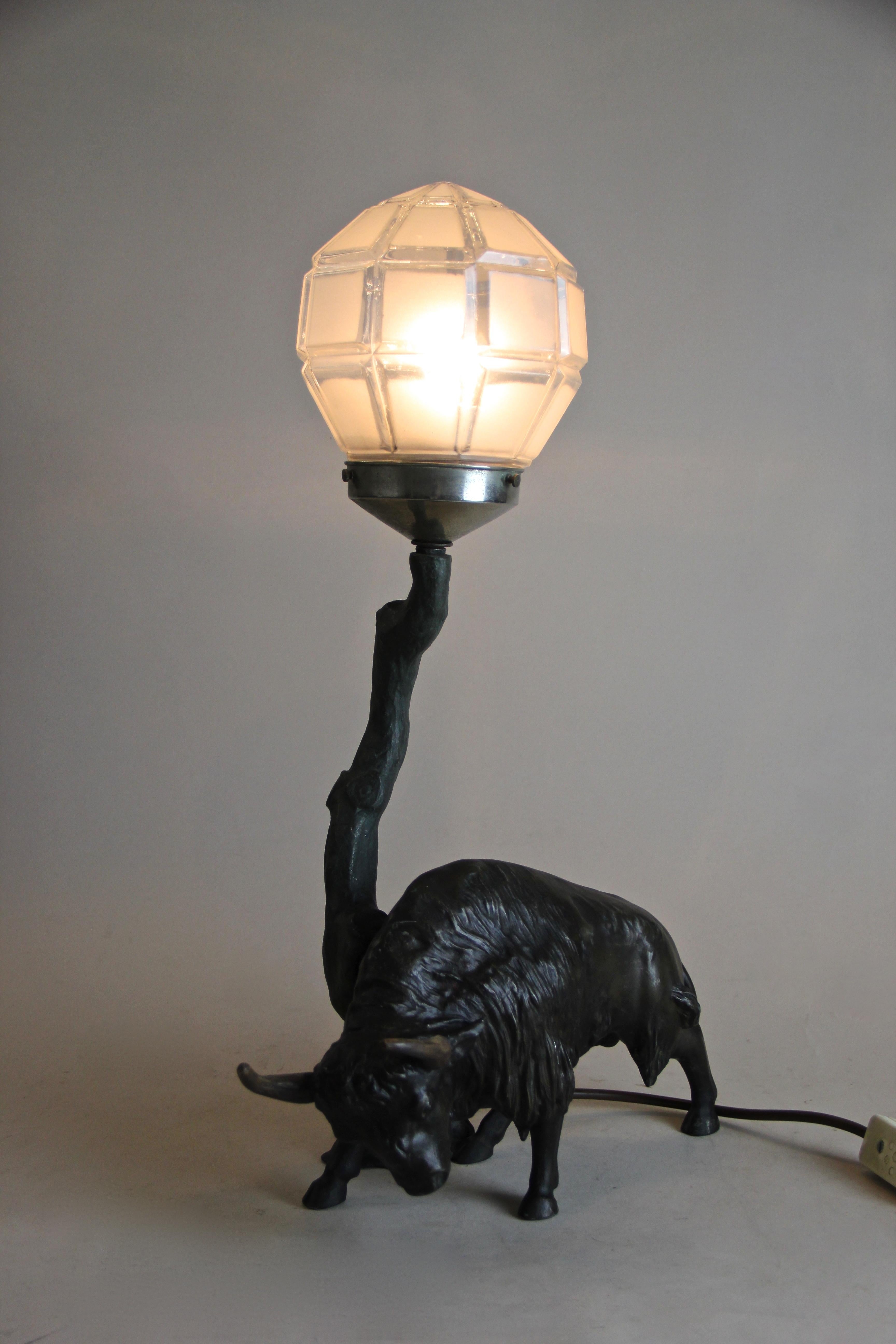 Extraordinary Spelter table lamp from the very early 20th century out of Austria. Depicting a majestic North American bison, this unique table lamp consists of a beautiful designed glass ball which sits on top of a narrow tree trunk, spreading a