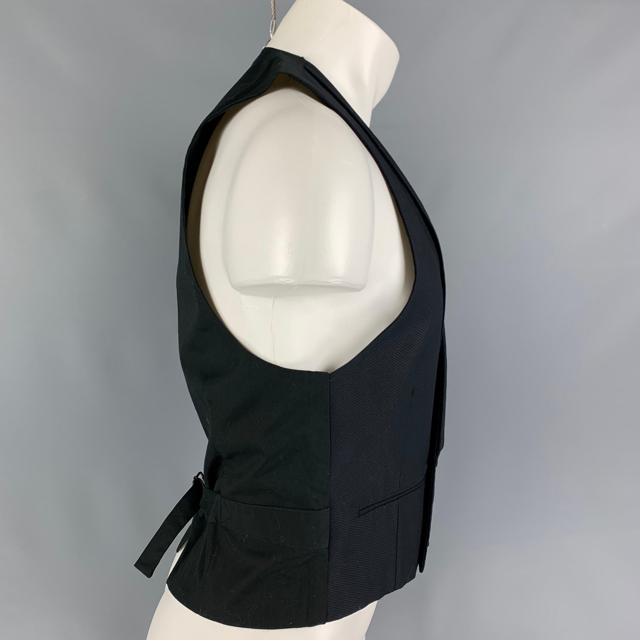 SPENCER HART vest comes in a black textured cotton featuring a shawl collar, slit pockets, adjustable back strap, and a double breasted closure.  

Excellent Pre-Owned Condition.
Marked: 36 L

Measurements:

Shoulder: 12.25 in.
Chest: 35 in.
Length: