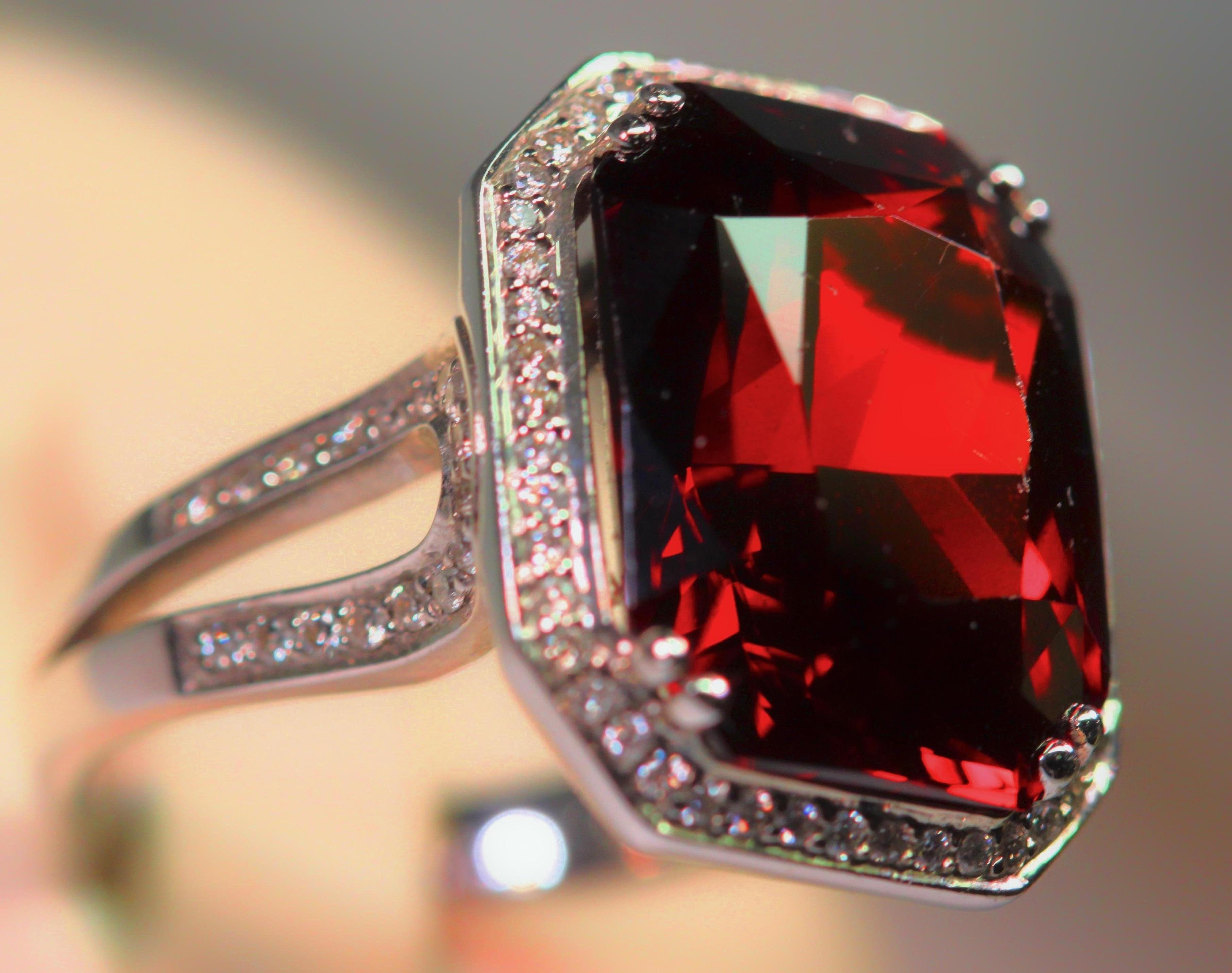 This is a phenomenal spessartite garnet, 18 karat white gold and diamond ring. The garnet's color is a bright rich red with slight brown under tones. The spessartite garnet is very lively with lots of flashing and it weighs 17.58 carats total
