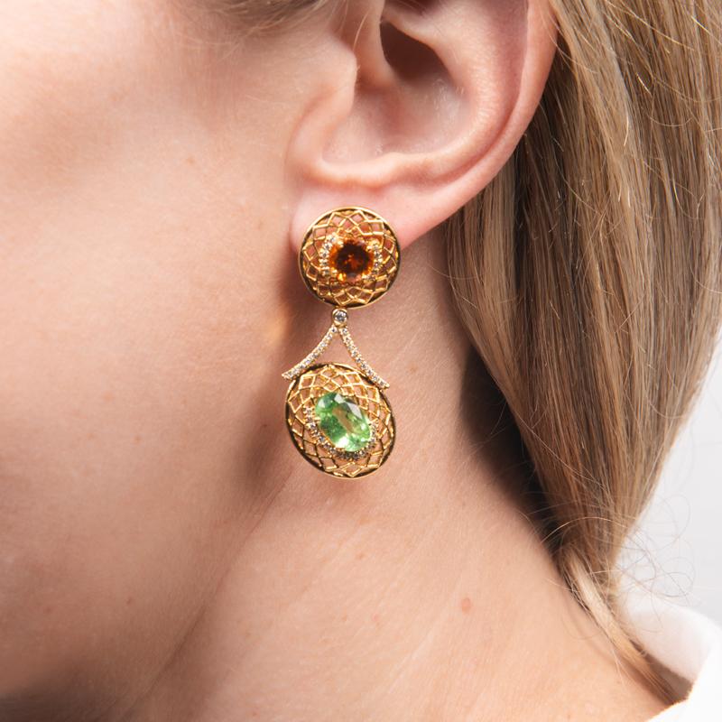 These stunning and vibrant earrings tell a story of an era of magical glamor and bold statements. Each earring features an oval and a round garnet in contrasting colors. 
Gemstone weights and shapes: 
Earring one: 3.46 carat oval spessartite garnet