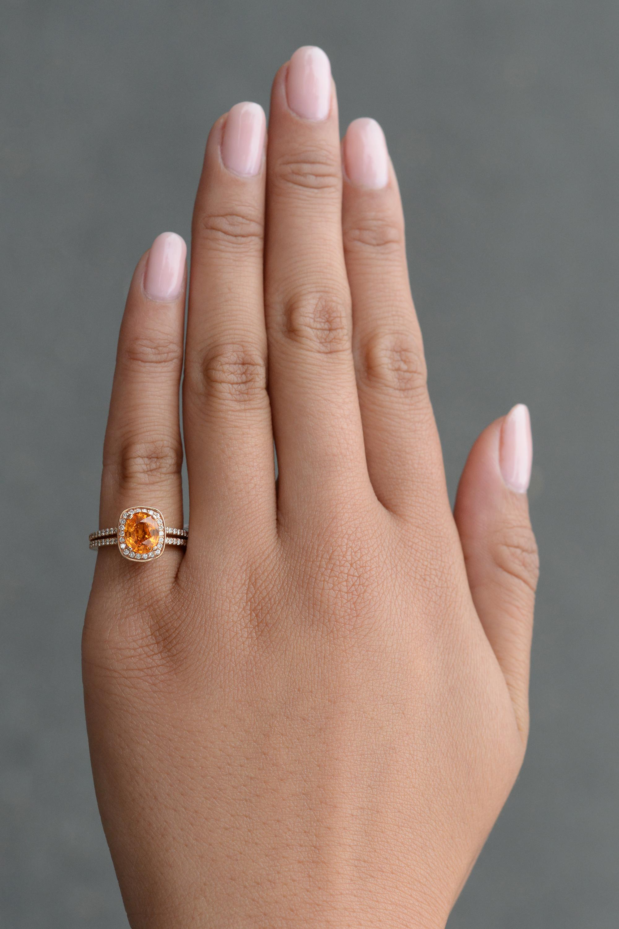 This glamorous gemstone engagement ring showcases a spectacular, seldom seen specimen. The spessartite garnet illuminates a vivid, glowing orange that is highly coveted. There is surely no lack of brilliance in this ring, featuring a halo of bright