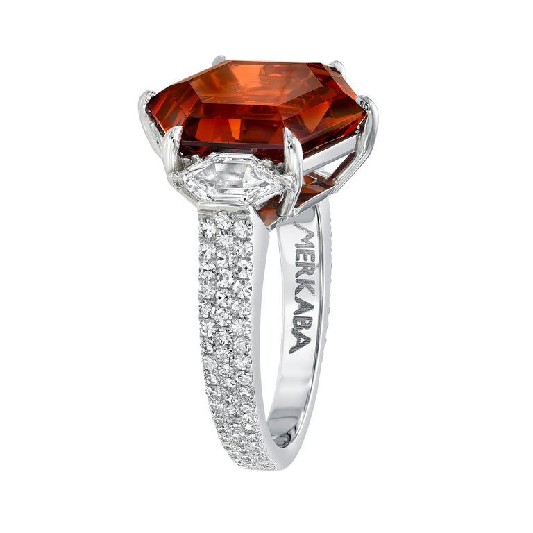 One of a kind 9.59 carat Spessartite Garnet platinum ring, flanked by a pair of F/VS1 hexagon diamonds totaling 0.59 carats, and decorated with a total of 0.53 carat round, single cut, collection diamonds.
Size 6. Re-sizing is complimentary upon