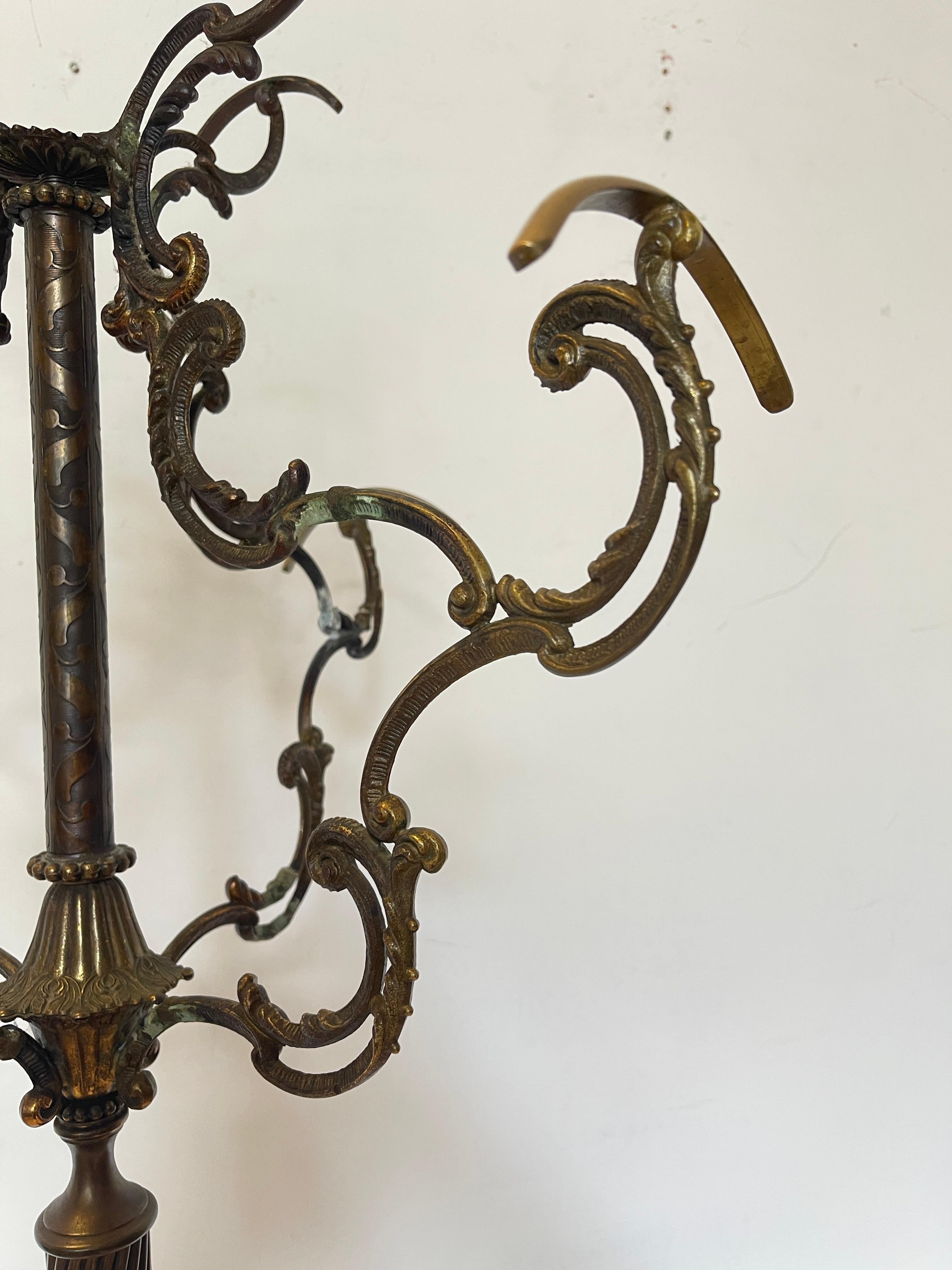 Forged bronze coat rack is an excellent example of high-quality craftsmanship, with an elegant structure and golden details that make it a true piece of furniture. The finely crafted central column with a spiral pattern is supported by an elegant