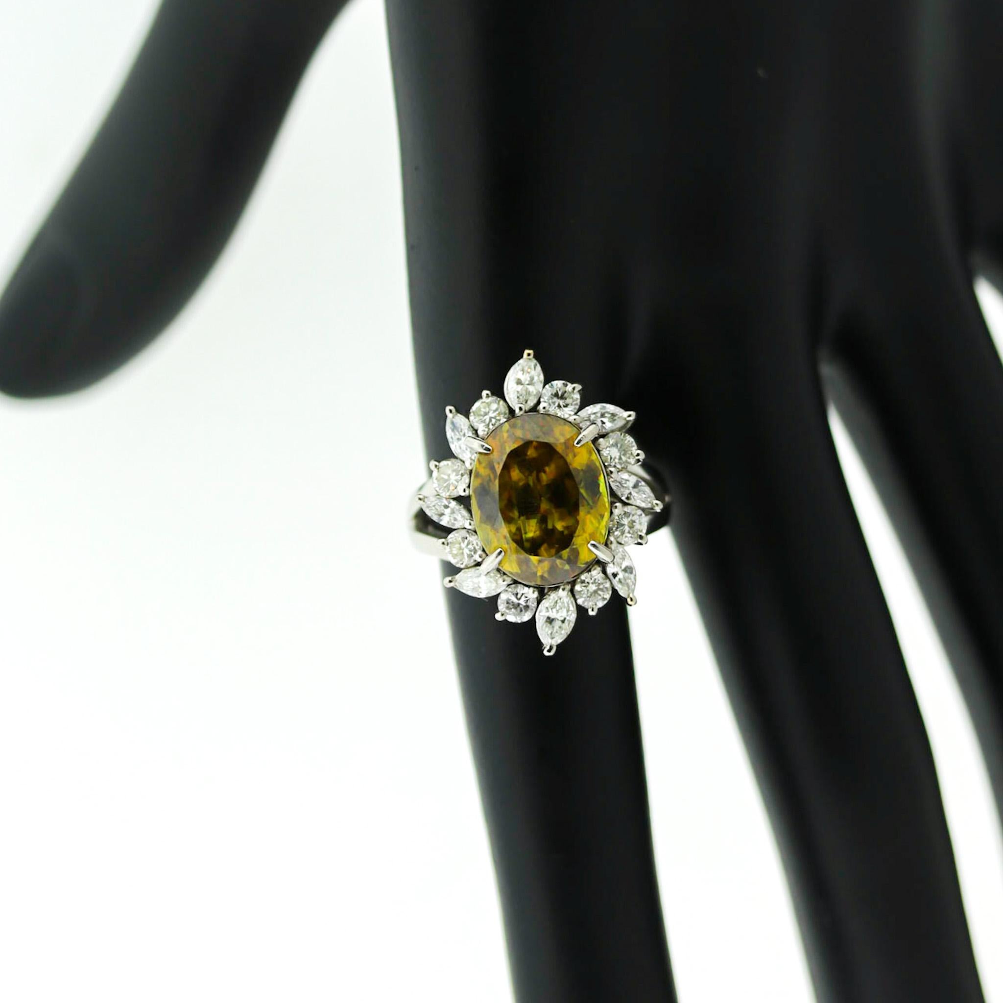 A beautiful sphene weighing 8.14 carats takes center stage of this fine platinum ring. It has very high dispersion, more than diamond, giving it amazing fire as a spectral array of colors can be seen flashing off its facets. It is accented by a halo