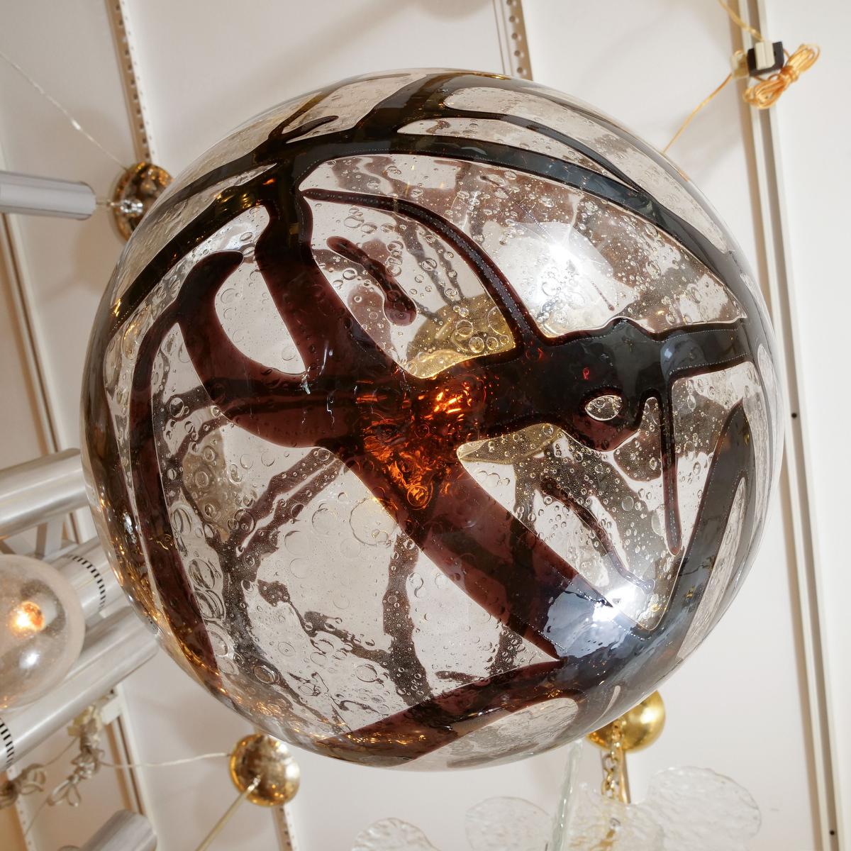 Spherical clear glass pendant with swirled amber design and brass hardware. In Good Condition In New York, NY