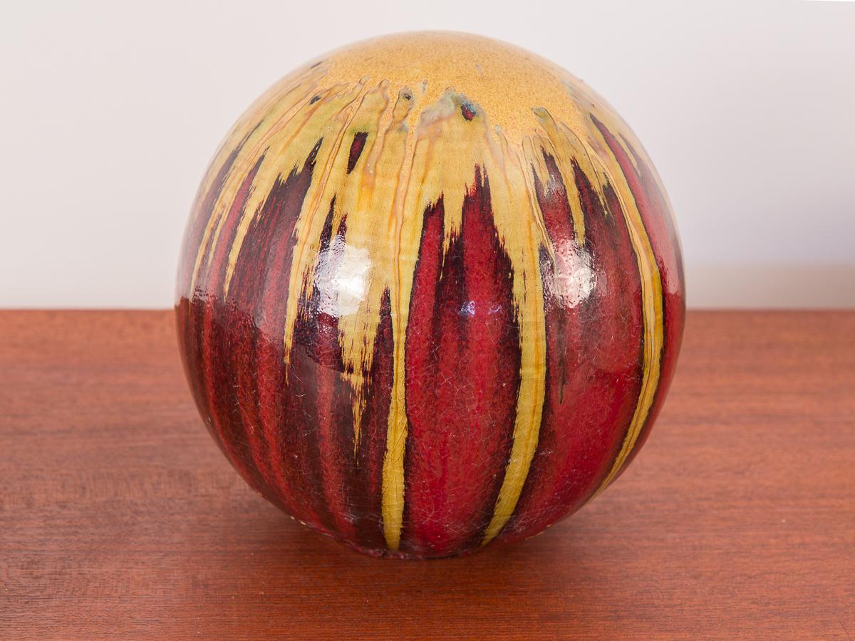 Stunning 1960s art pottery table sculpture. Gold drip glaze melds into dark layers of brick red hues covering the spherical form. Finish is even and lustrous. Hollow inside. Excellent condition.