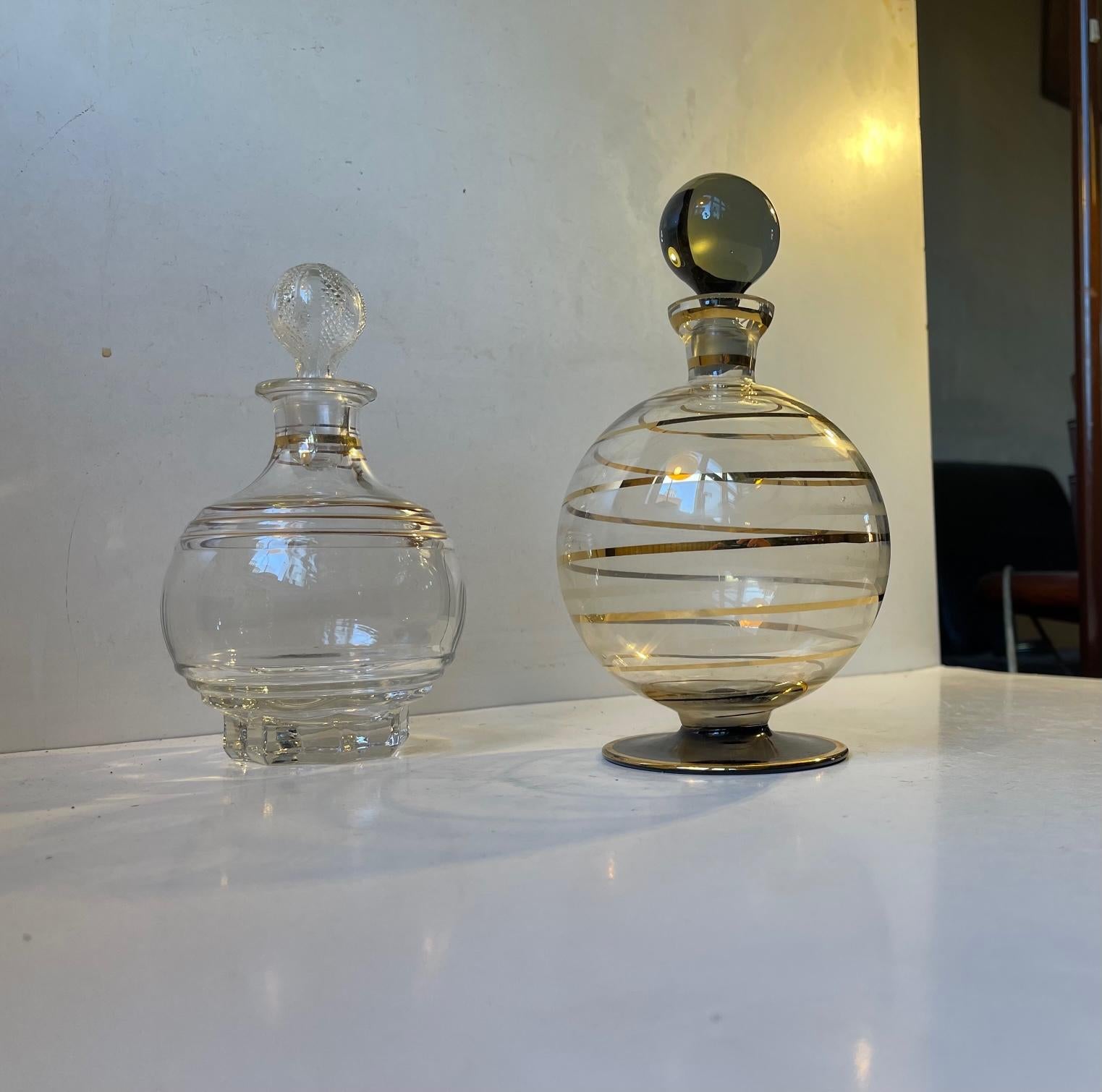A set of ball-shaped decanter. One hand-blown and decorated with gold glaze and black glass and one in pressed glass with gold stripes. They were both manufactured in Italy between 1950-70s. Measurements: H: 22/19 cm, D: 14/11 cm. Capacity: circa