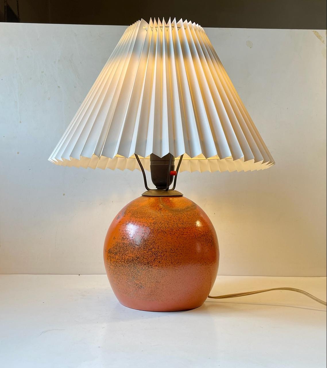 Playfully glazed spherical pottery table light in the style of Jean Besnard. Designed and created by anonymous designer/maker in France during the 1920s or 1930s. No markings or signature to the base. It features period bakelite socket and bronze