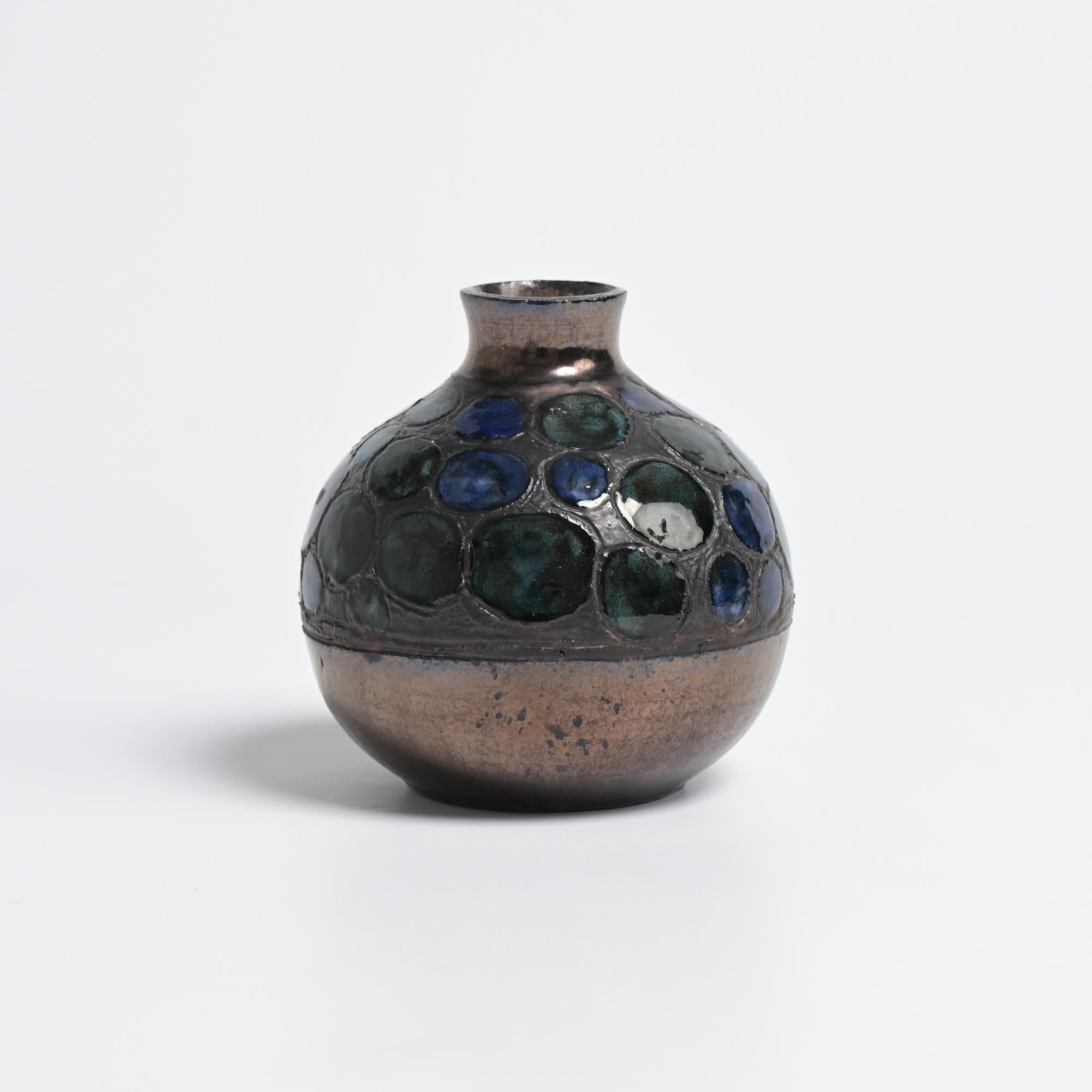 This spherical vase was created in the workshop of Perignem in Beernem, Belgium. We date it back to the 1960s.

The base of this vase has a bronze glaze finish. The top was complemented by glazed dots with colors ranging from dark blue to sea