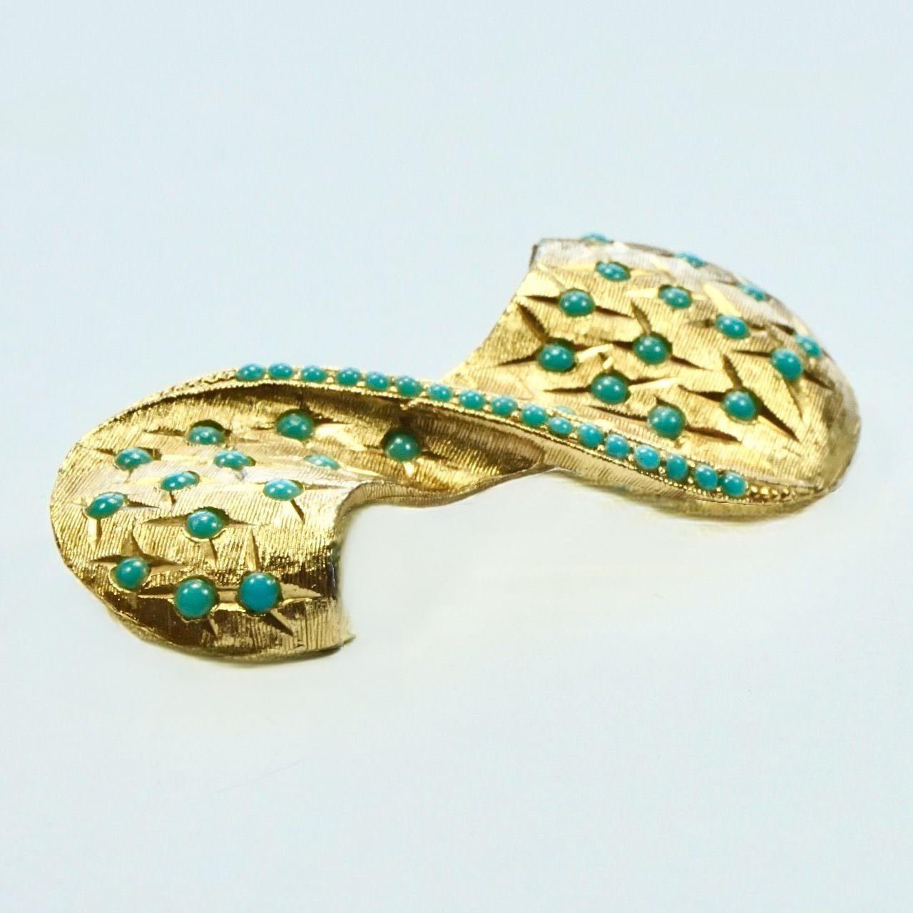 Merveilleuse broche abstraite Sphinx en plaqué or, décorée d'un motif de pierres de verre turquoise et taillées en diamant. Longueur 5,5 cm / 2,1 pouces et largeur maximale 2,6 cm / 1 pouce.

Cette jolie broche de Sphinx date des années