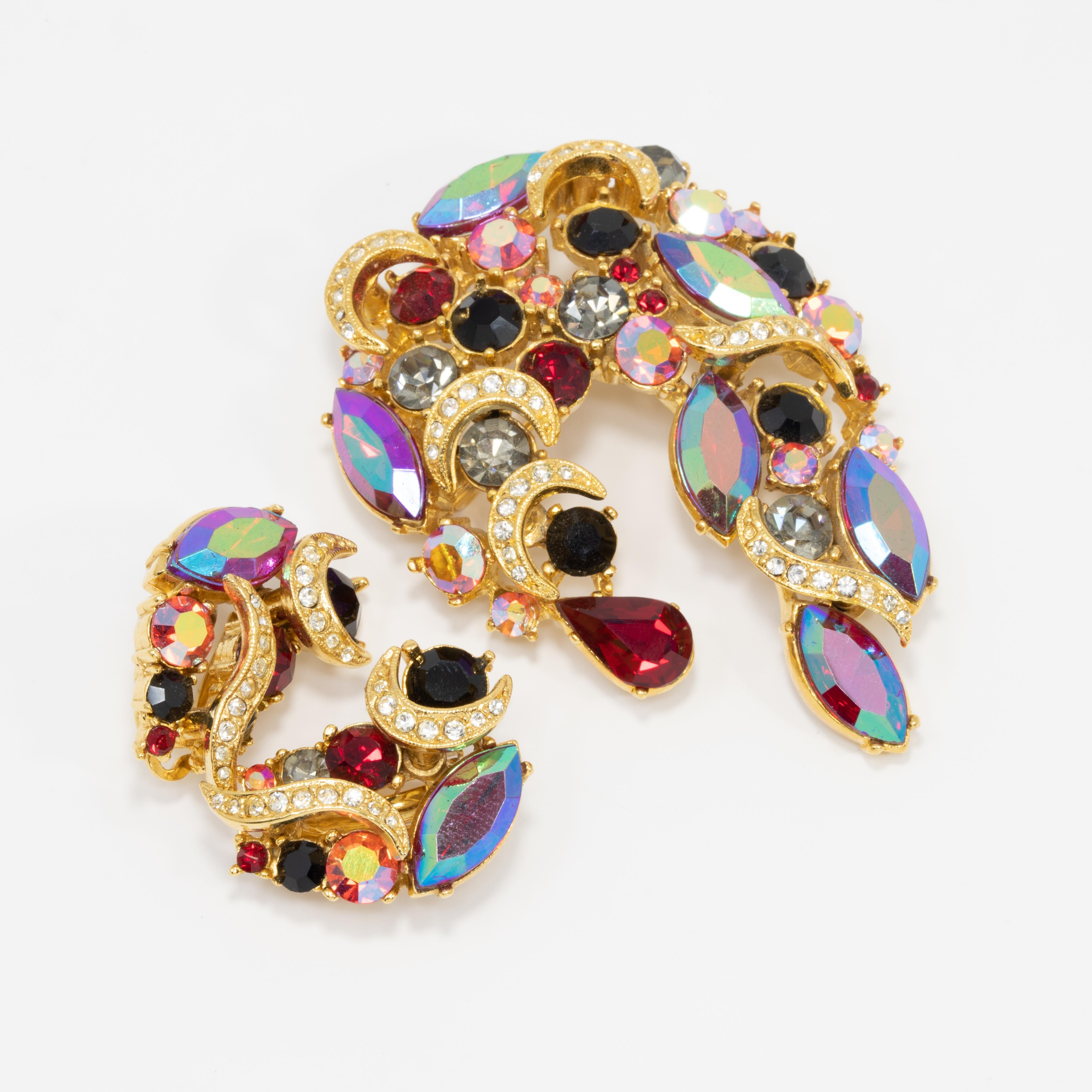 A matching pin and pair of clip on earrings by Sphinx, featuring siam-red aurora borealis crystals prong-set in a decorative gold-plated setting.

Pin dimensions: 2.7 in x 1.9 in
Earring dimensions: 1 in x .7 in

Hallmarks: Sphinx (pin and both
