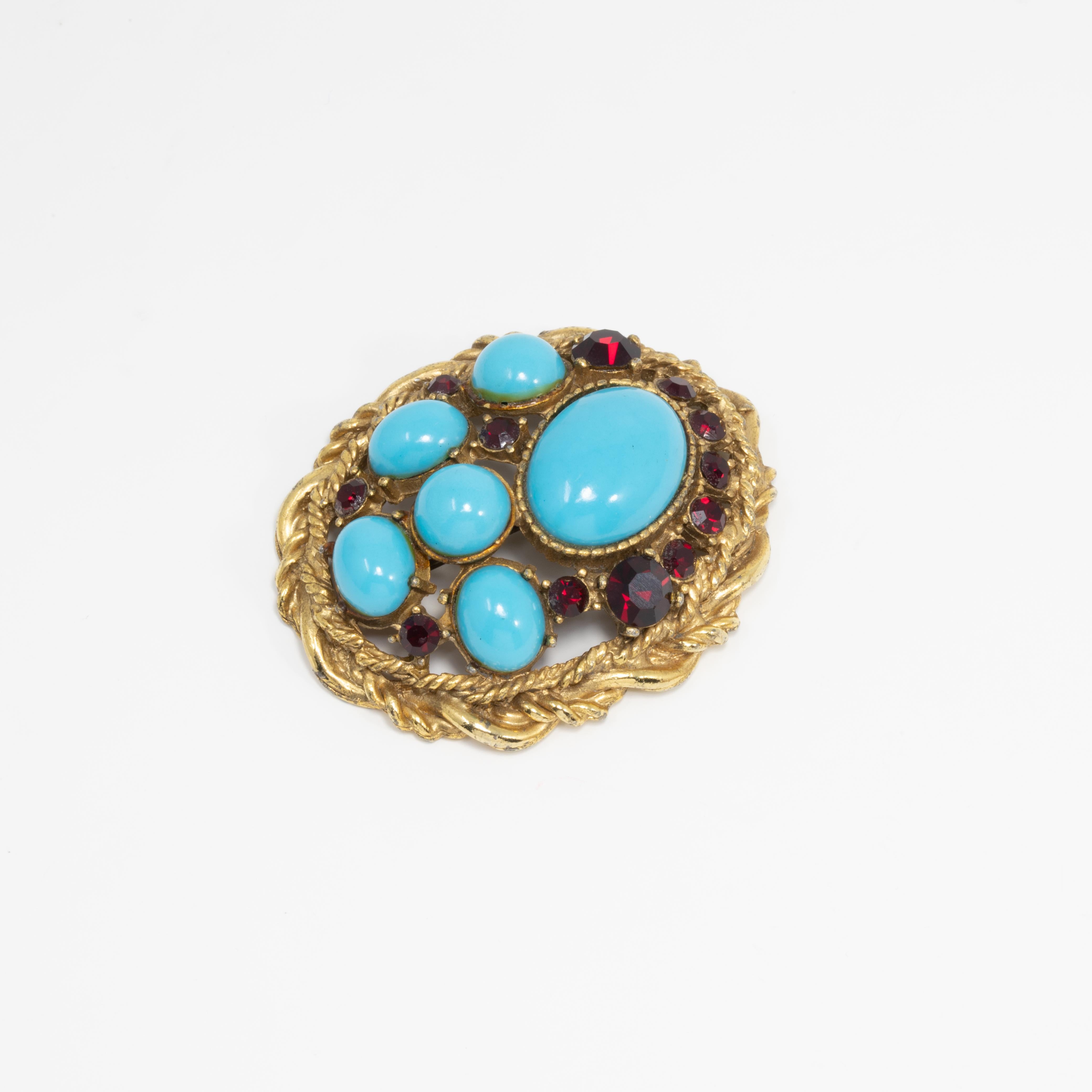 Vintage pin by costume jewelry designer Sphinx, featuring turquoise-colored cabochons and ruby-red crystals. Set in an oval, floral wreath motif gold plated setting.

Hallmarks: Sphinx, A1159