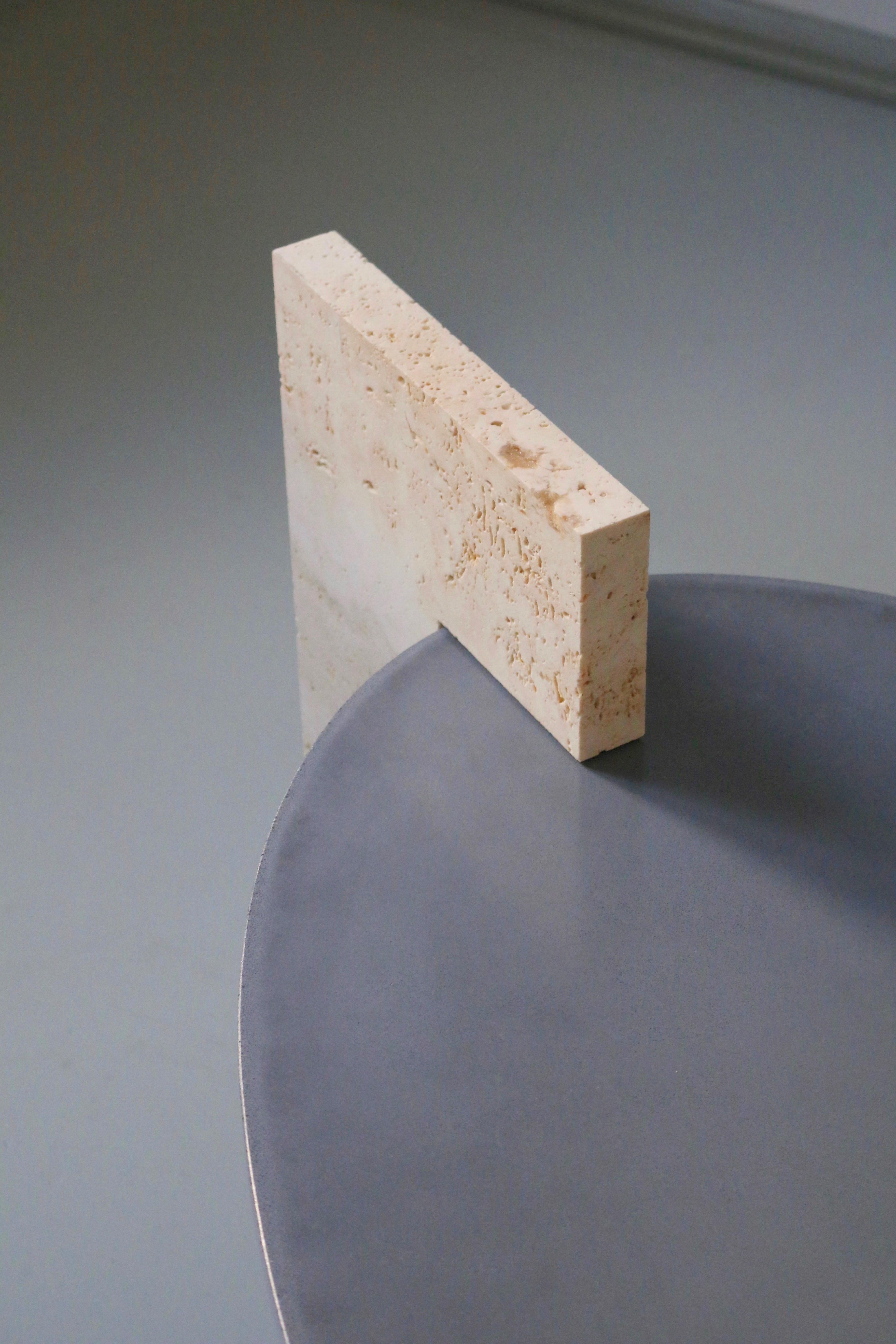 Table basse contemporaine minimaliste SPHINX en béton bicolore et pierre de travertin. Dessus et pieds ovales en béton étanche scellé, complétés par une 