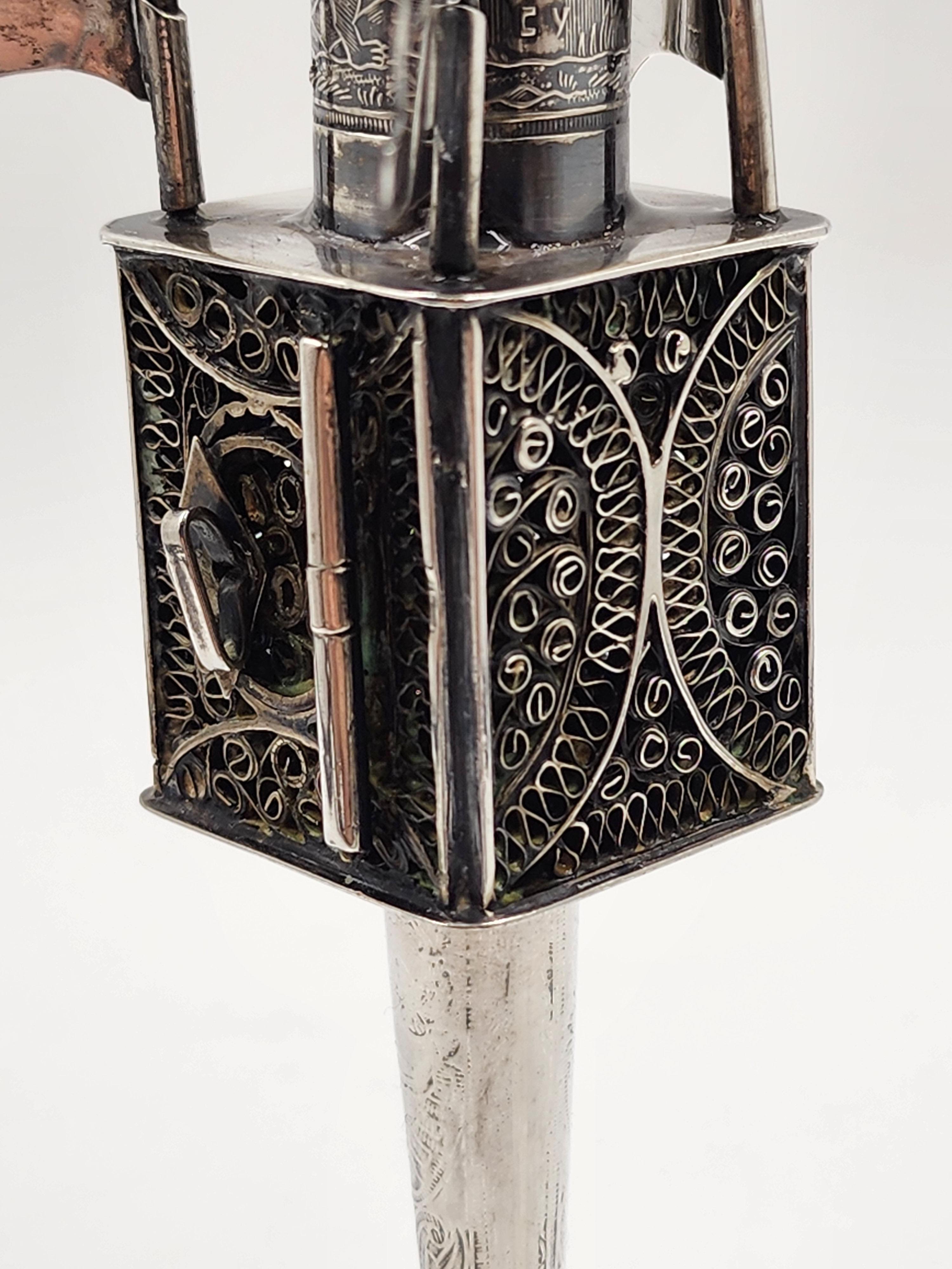 Torre delle spezie in argento giudaico, XX secolo
Una bella torre di spezie dal design tipico, con quattro bandiere; la torre è sormontata da una piccola palla. Posizionato su una gamba rotonda. Decorato con filigrana e incisioni.
Misure:
Altezza: