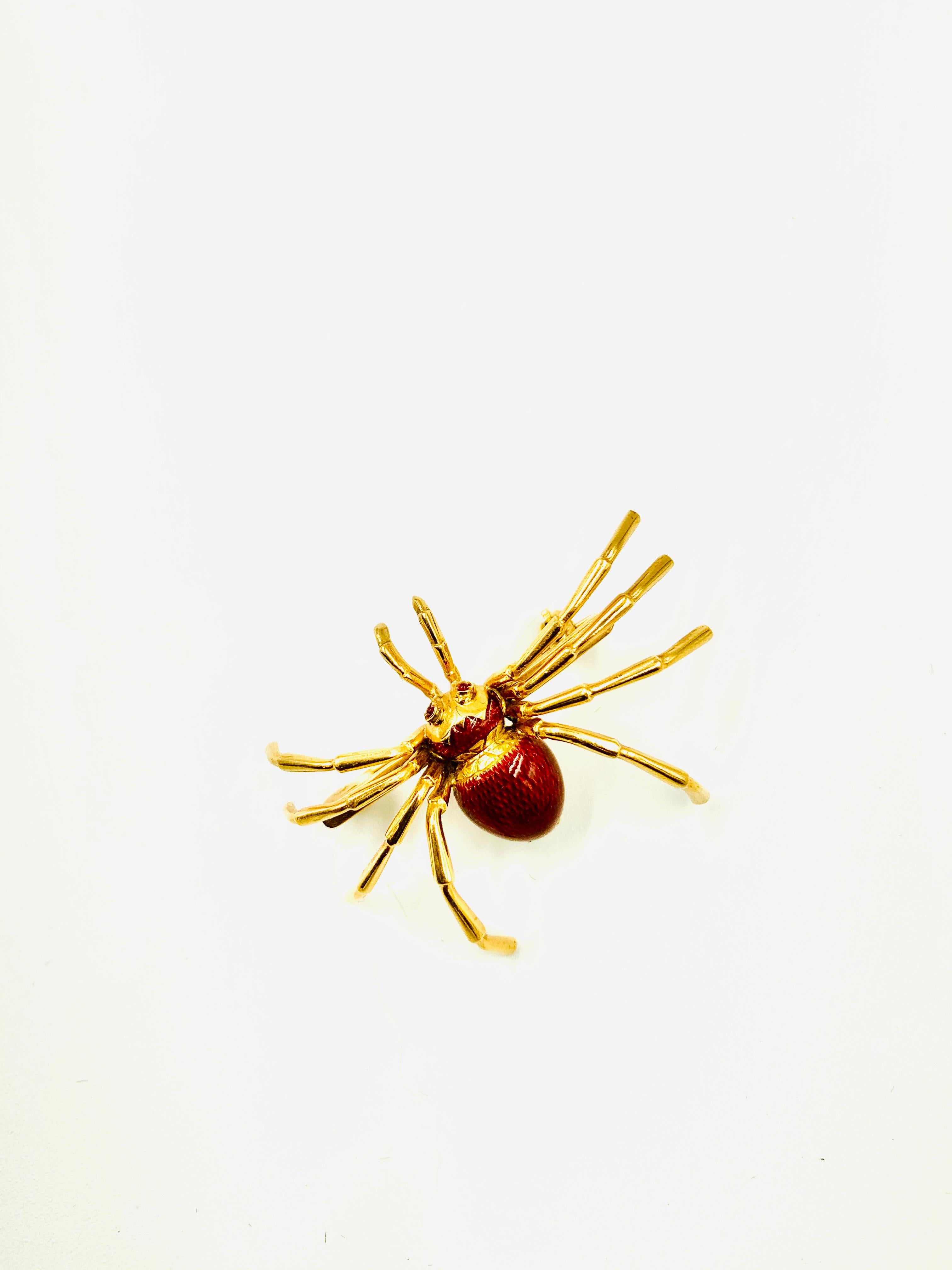 Naturalistically modeled spider brooch in 18k gold with rich red guilloche enameled body and cabochon ruby eyes. 
20th Century
The spider represents mystery, power and spiritual growth. Other spider symbolisms are patience, good timing and the