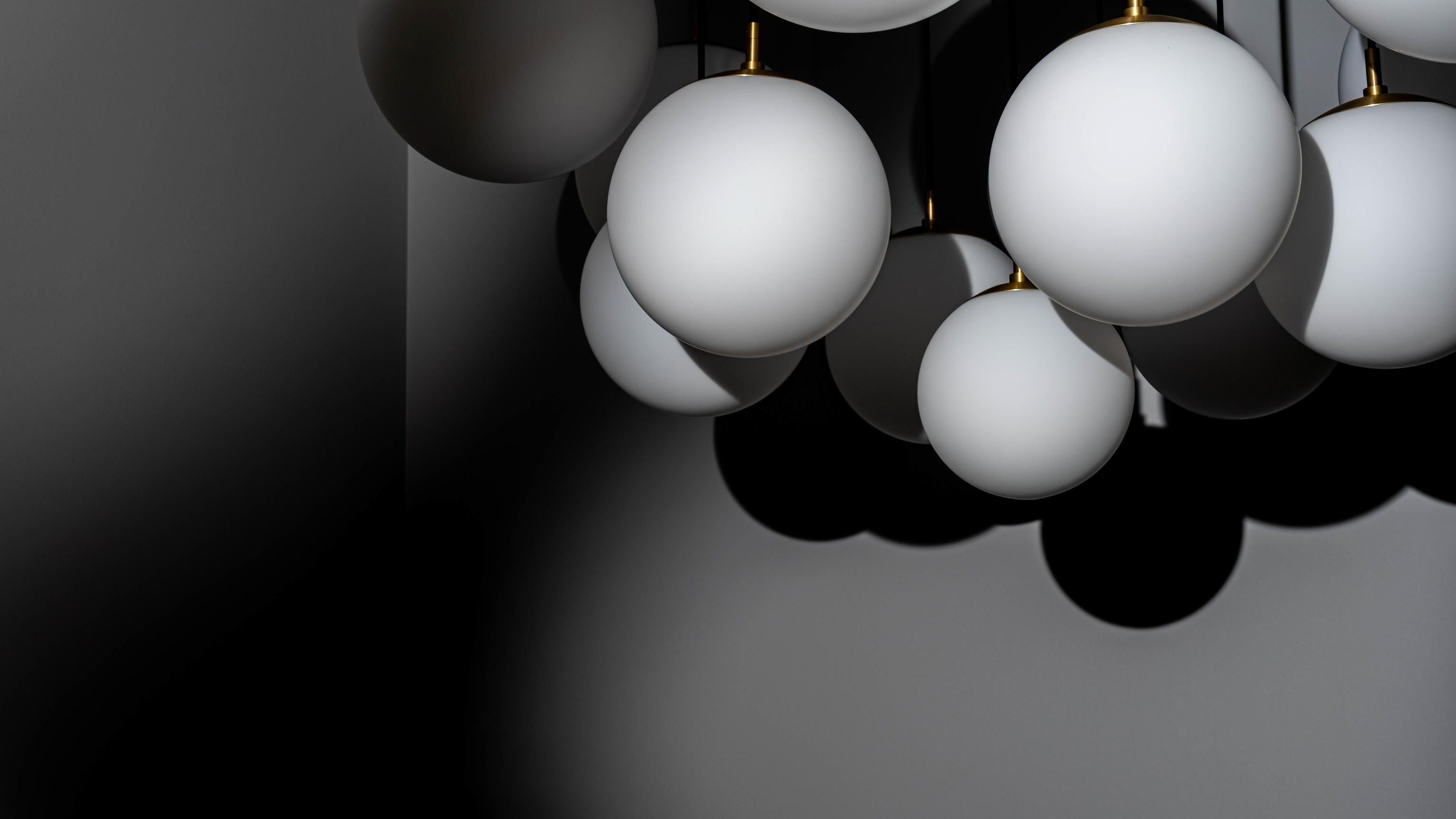 Una serie di tredici globi è sospesa in modo drammatico. Lo spettacolare drappeggio dei cavi scuri crea una ragnatela che sfida la gravità, un vivaio con una cascata di sfere luminose. La forma rende omaggio alla bellezza inquietante dell'aracnide,