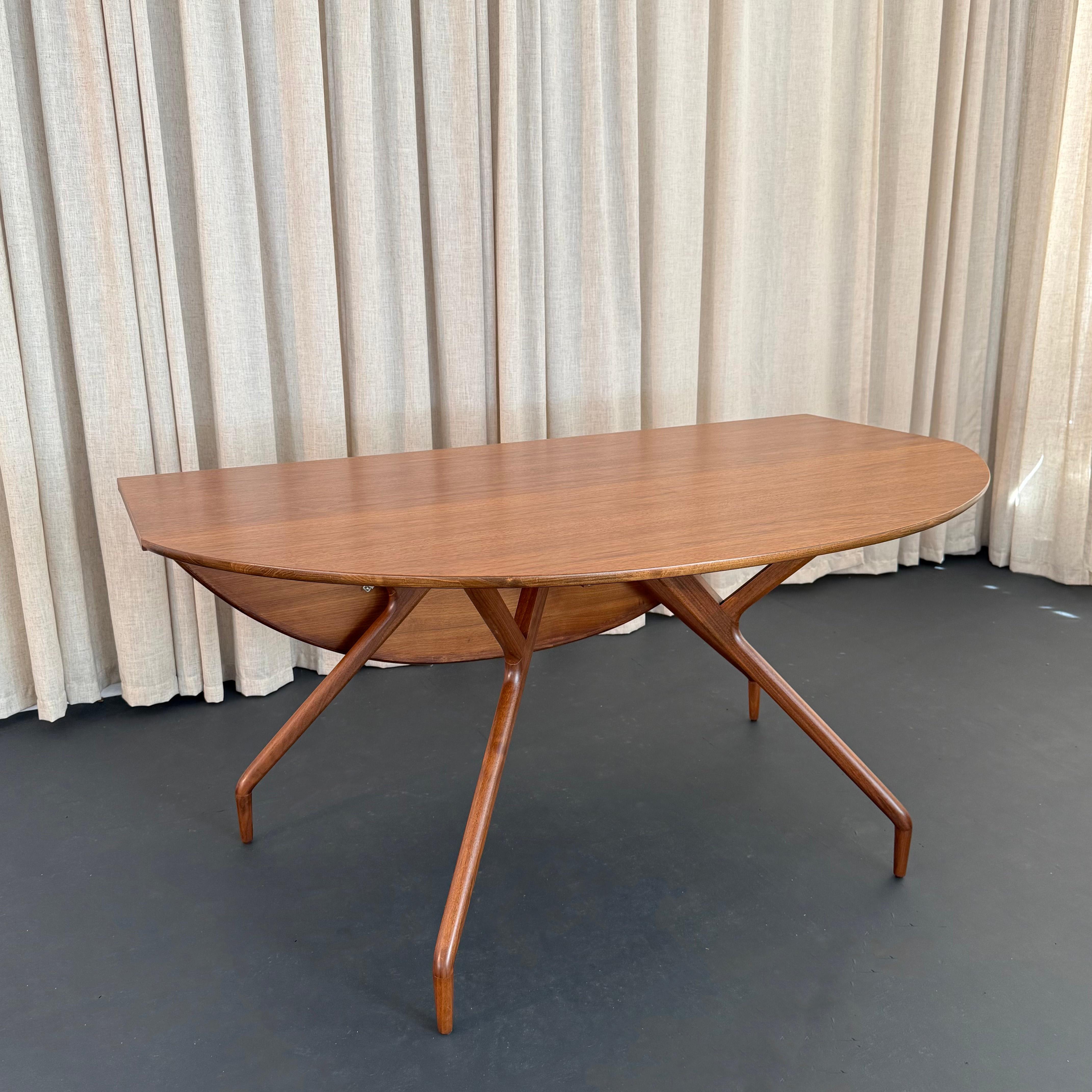 This iconic Mid-Century Modern walnut drop-leaf dining table with spider leg design was created by the Swedish-American designer Greta Magnusson Grossman for Glenn of California c. 1952. The table features a unique design with slender, sculpted
