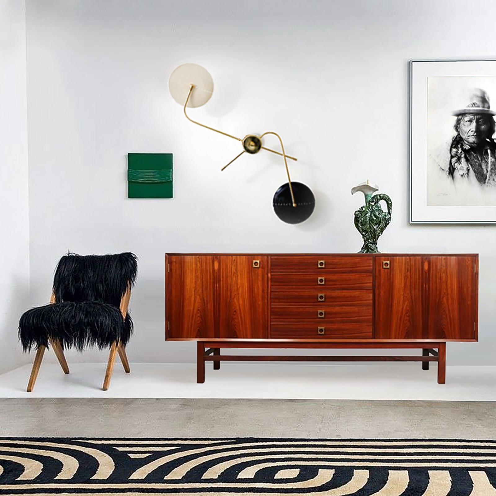 Ispirata al design italiano del Mid-Century, questa applique sarà il centro dell'attenzione dei tuoi interni. Due bracci che attraversano il centro, ciascuno dei quali termina con un paralume in alluminio laccato, progettato con una linea di