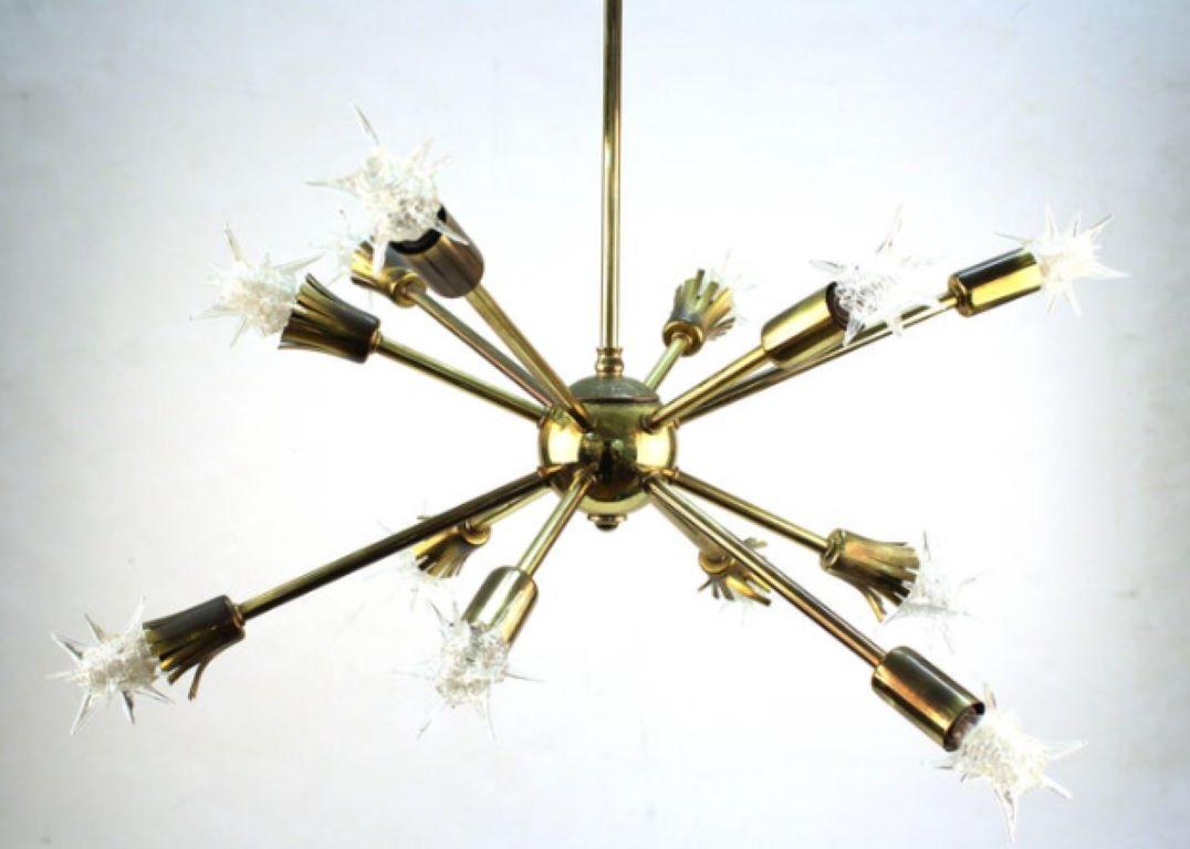 A brass Sputnik chandelier with twelve arms, several with a tasseled end. The chandelier includes spiked glass bulb caps for each arm. Despite some tarnish and wear the chandelier remains in good vintage condition. The length of the bulb caps are