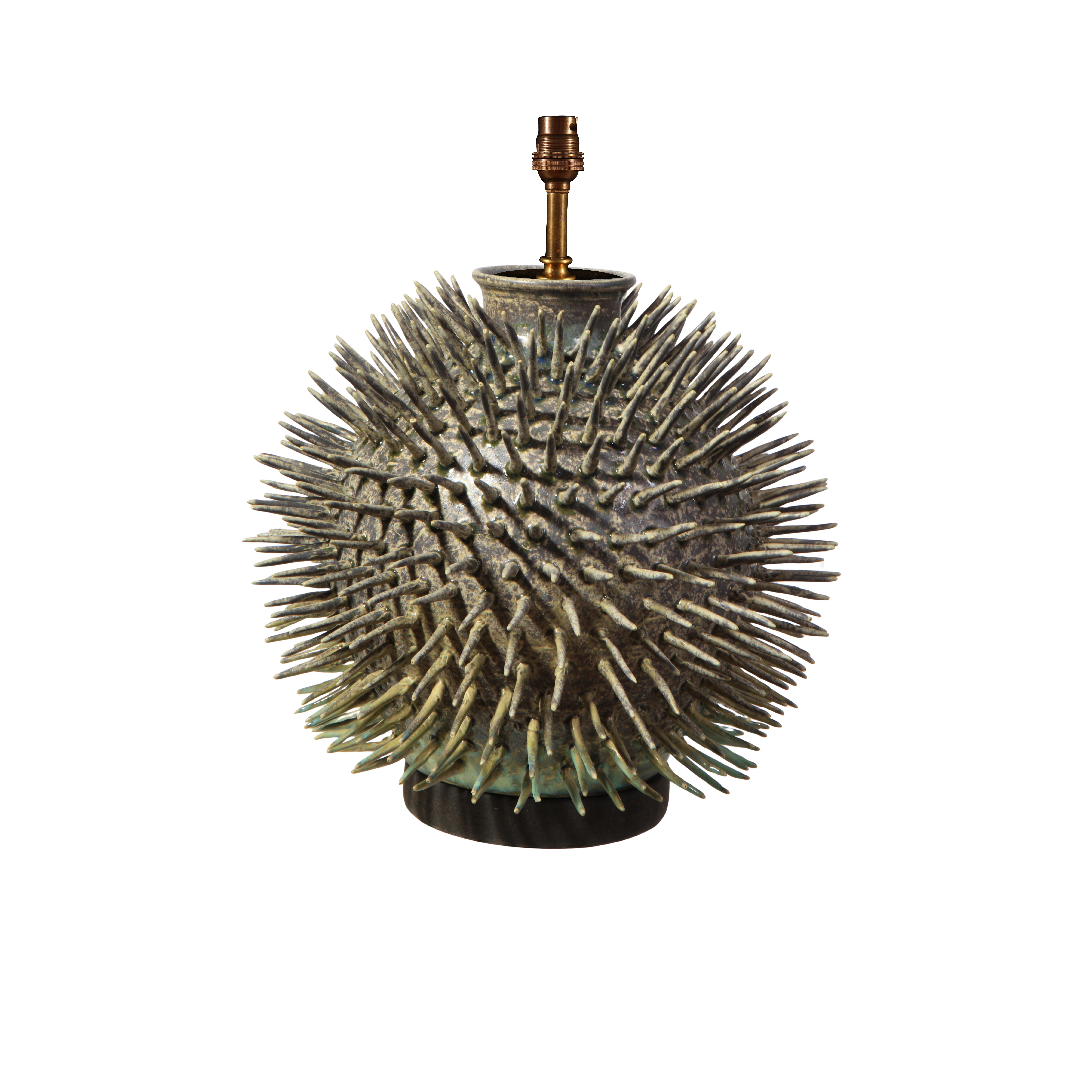 Cette lampe contemporaine saisissante, à la forme sculpturale audacieuse, est fabriquée à la main au Royaume-Uni à partir de porcelaine fine. La base sphérique est ornée de détails dynamiques en forme de pointes rappelant les oursins ou les