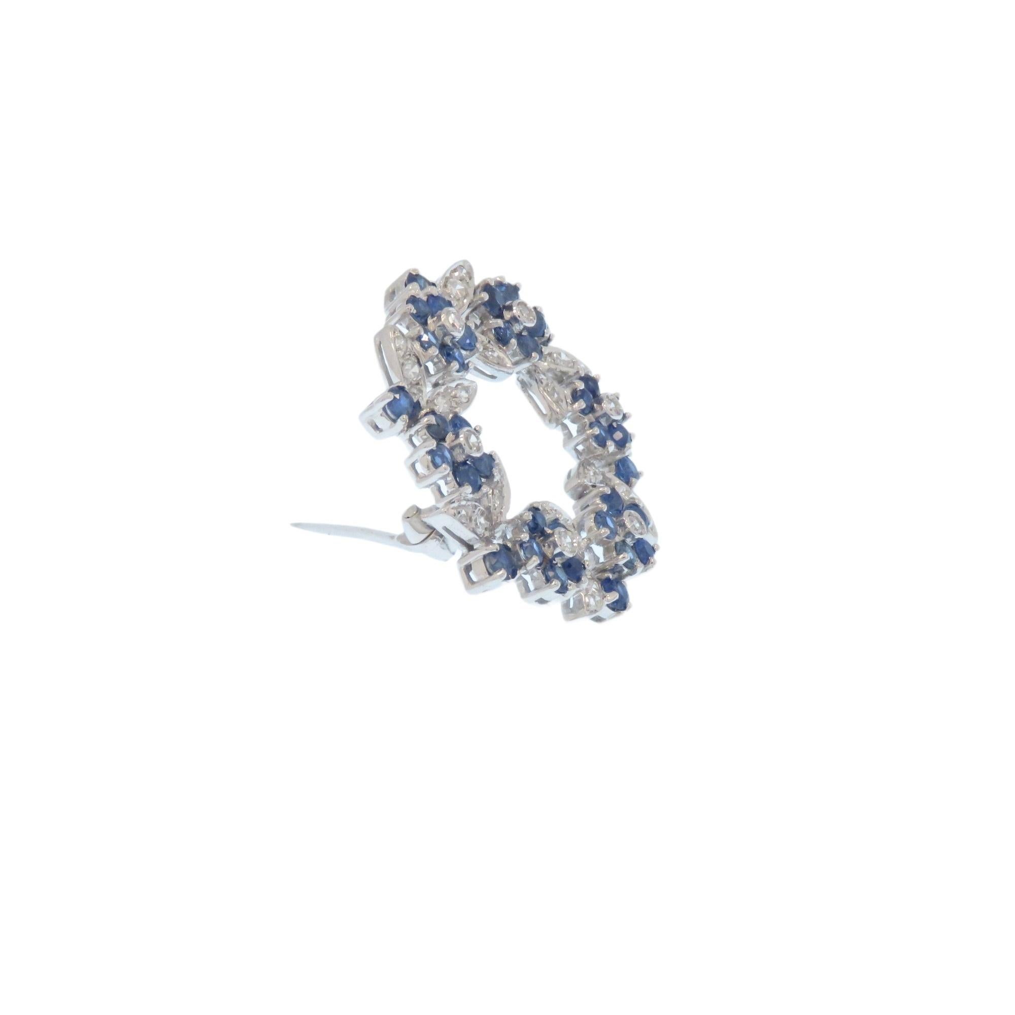 Disegnato con grappoli di fiori e foglie che si alternano a forma circolare. Realizzata nel 1960 in oro bianco 18 carati con diamanti e zaffiri blu.
36 diamanti a taglio brillante di 0.70 ctw circa e 36 zaffiri blu taglio brillante di 1.50 ctw