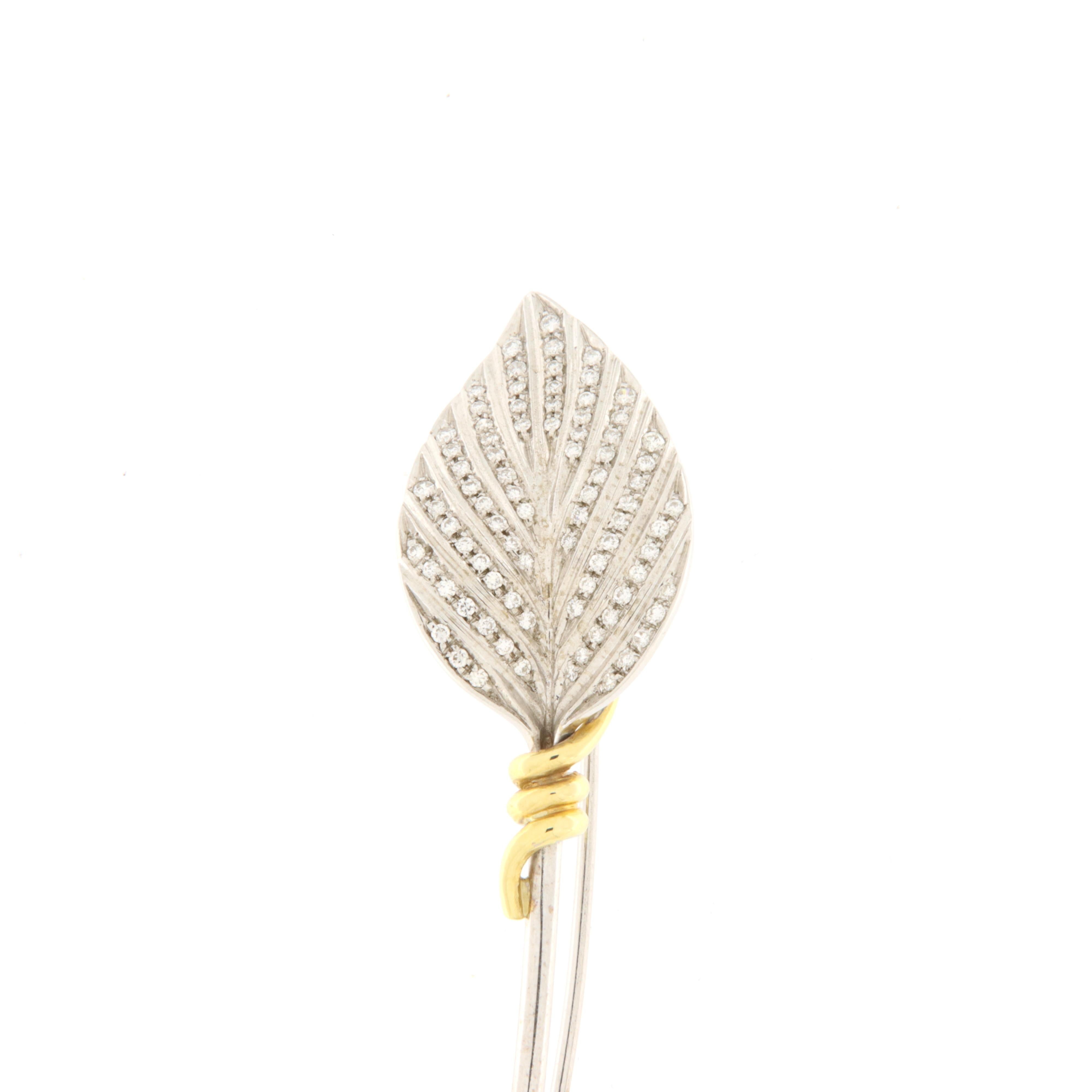 Delicate and highly refined white gold brooch in the shape of a leaf with brilliants (ct.0.55) and yellow gold detail that introduces the stem, all in white gold, elongated to give momentum and elegance to this piece of jewelry.