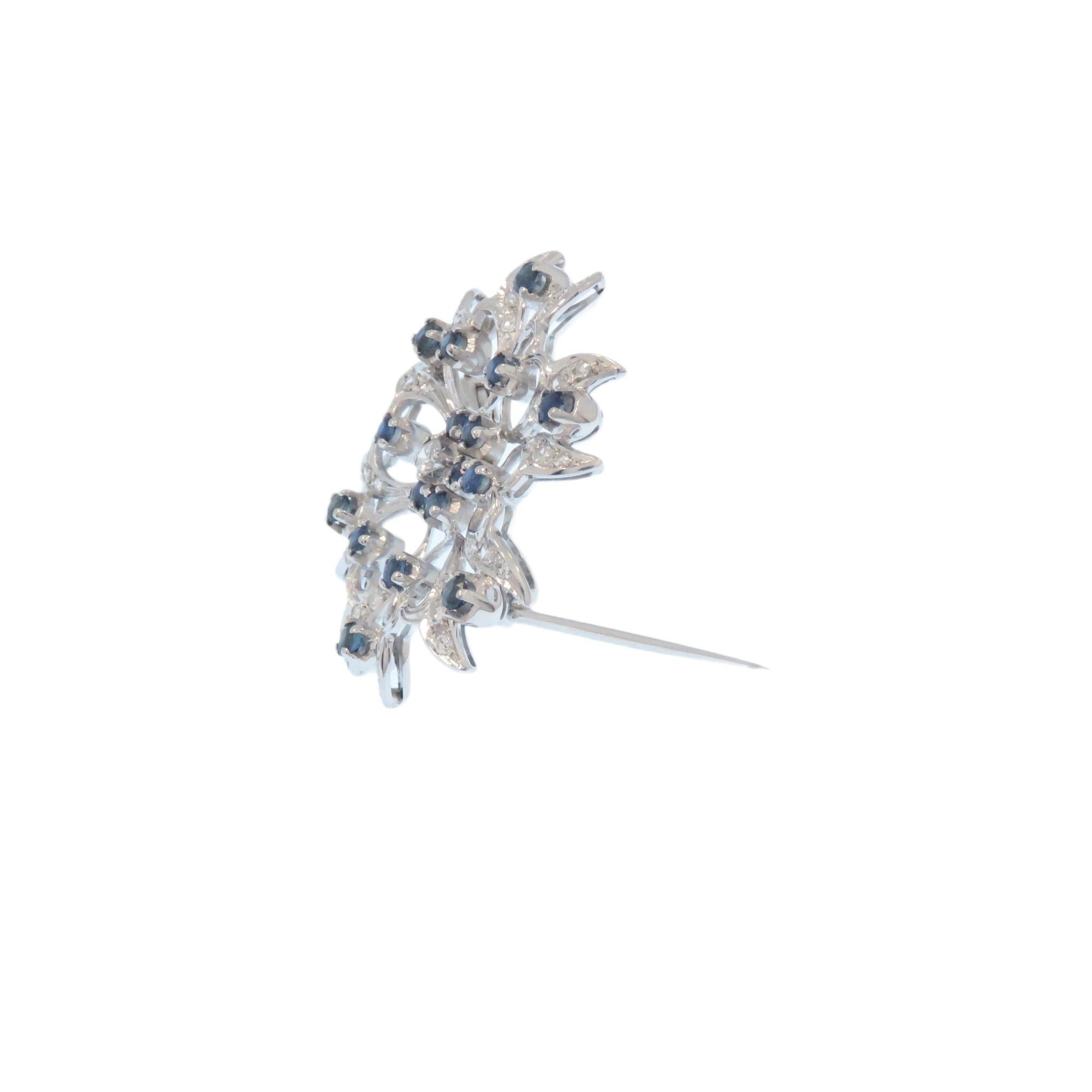 Jolie broche en or blanc 18 carats avec diamants et saphirs bleus, datant de 1960.
37 diamants taille brillant d'environ 0,80 ctw et 18 saphirs bleus taille brillant d'environ 0,90 ctw. Cette belle broche est fixée au dos par une épingle à charnière