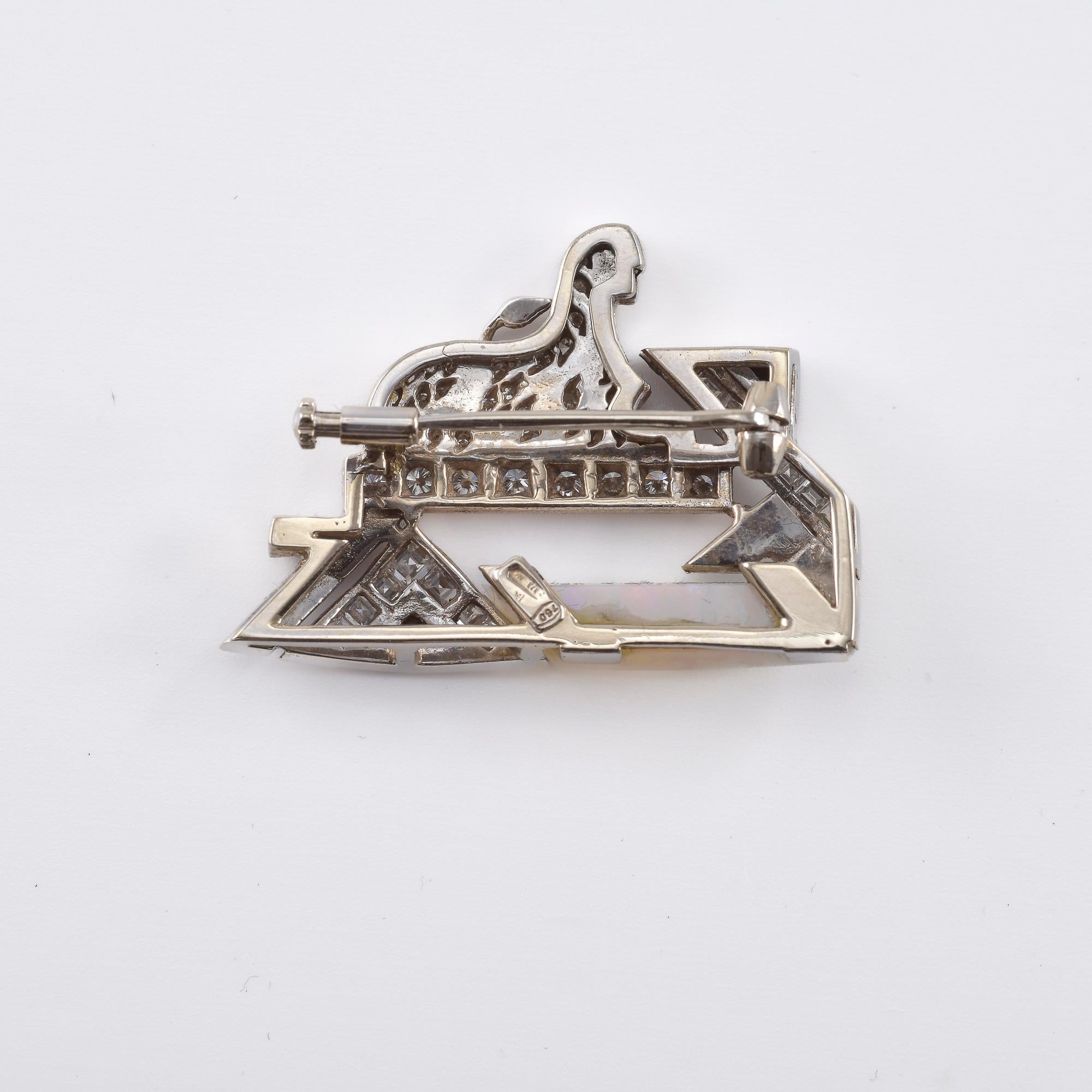 Brosche aus 18 Karat Weißgold (750/1000), markiert '750', mit einem ägyptischen Motiv aus Diamanten, schwarzem Onyx und edlem Opal.
Das Gesamtgewicht beträgt 10,52 Gramm.
Eine detaillierte Beschreibung der gemmologischen Merkmale finden Sie weiter