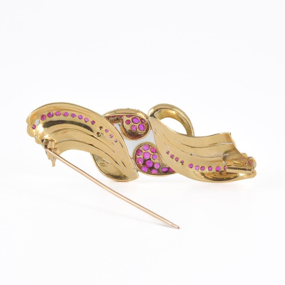 Broche raffinée en or jaune 18 carats à motif floral, ornée de 54 rubis naturels de taille ovale d'un rouge profond. Chaque détail est finement travaillé, avec une élégante combinaison de l'éclat de l'or et de la chaleur des rubis, idéale pour