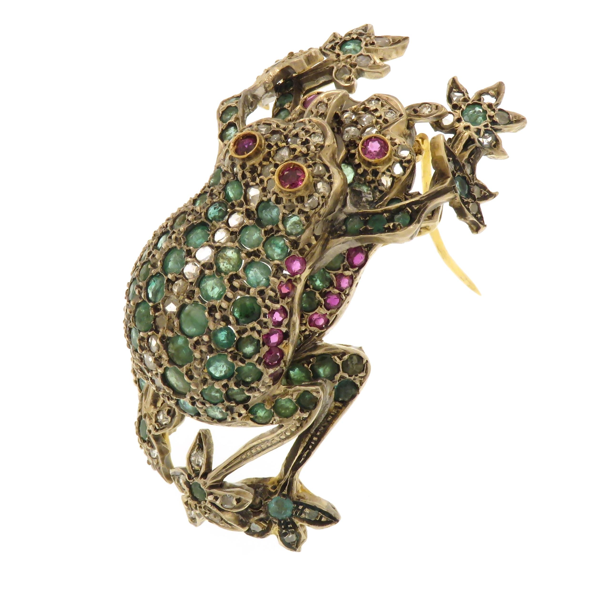 Extraordinary antique brooch dating from about 1920 hand-created in silver and 18k yellow gold with 78 diamonds, 94 emeralds and 24 rubies. It is definitely a finely crafted unique brooch depicting two overlapping frogs completely set with precious