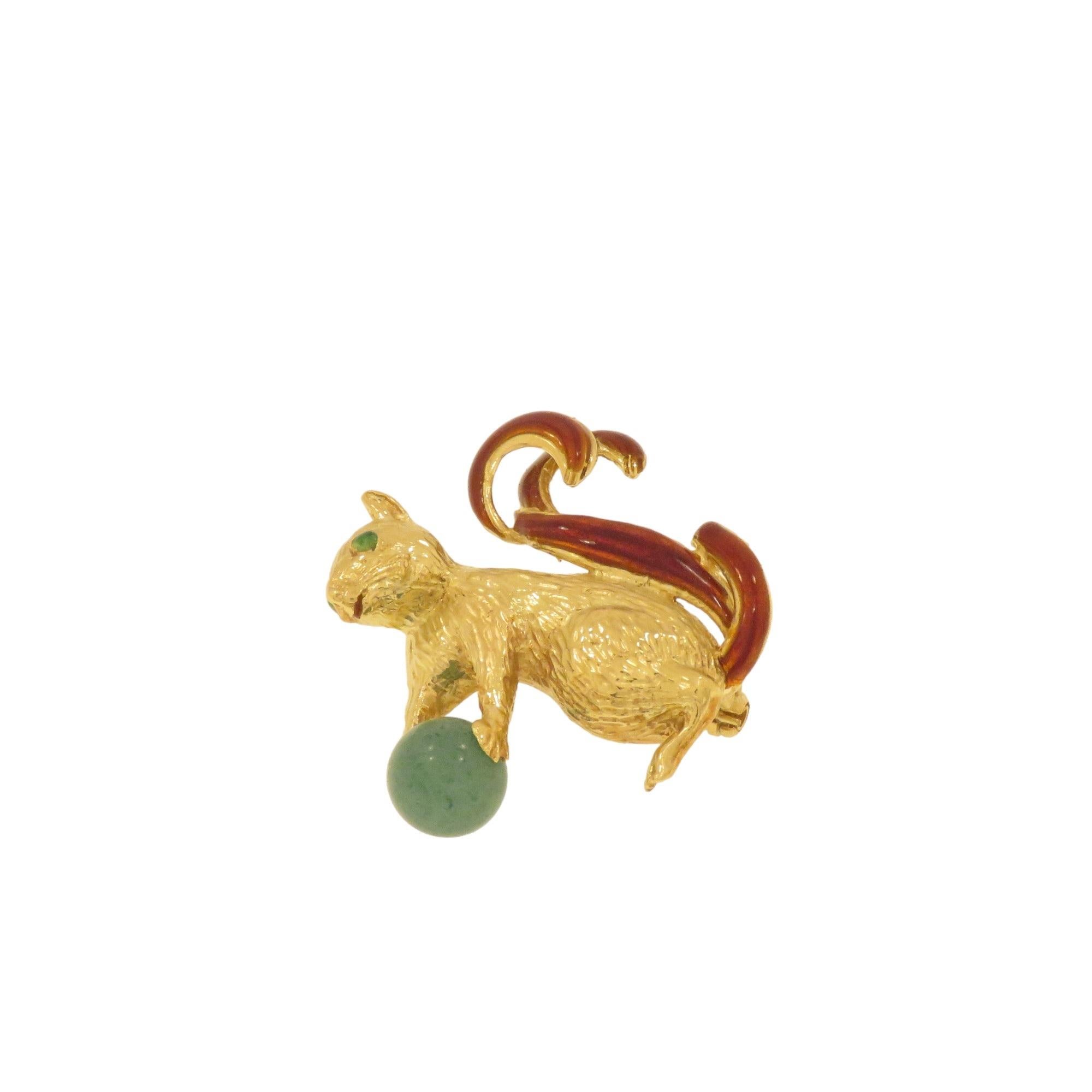 Ravissante broche représentant un écureuil, réalisée à la main en or 18 carats entre 1960 et 1970. L'écureuil tient entre ses pattes une sphère de jade et dans ses yeux sont serties deux petites émeraudes taillées en cabochon. Le corps est gravé à