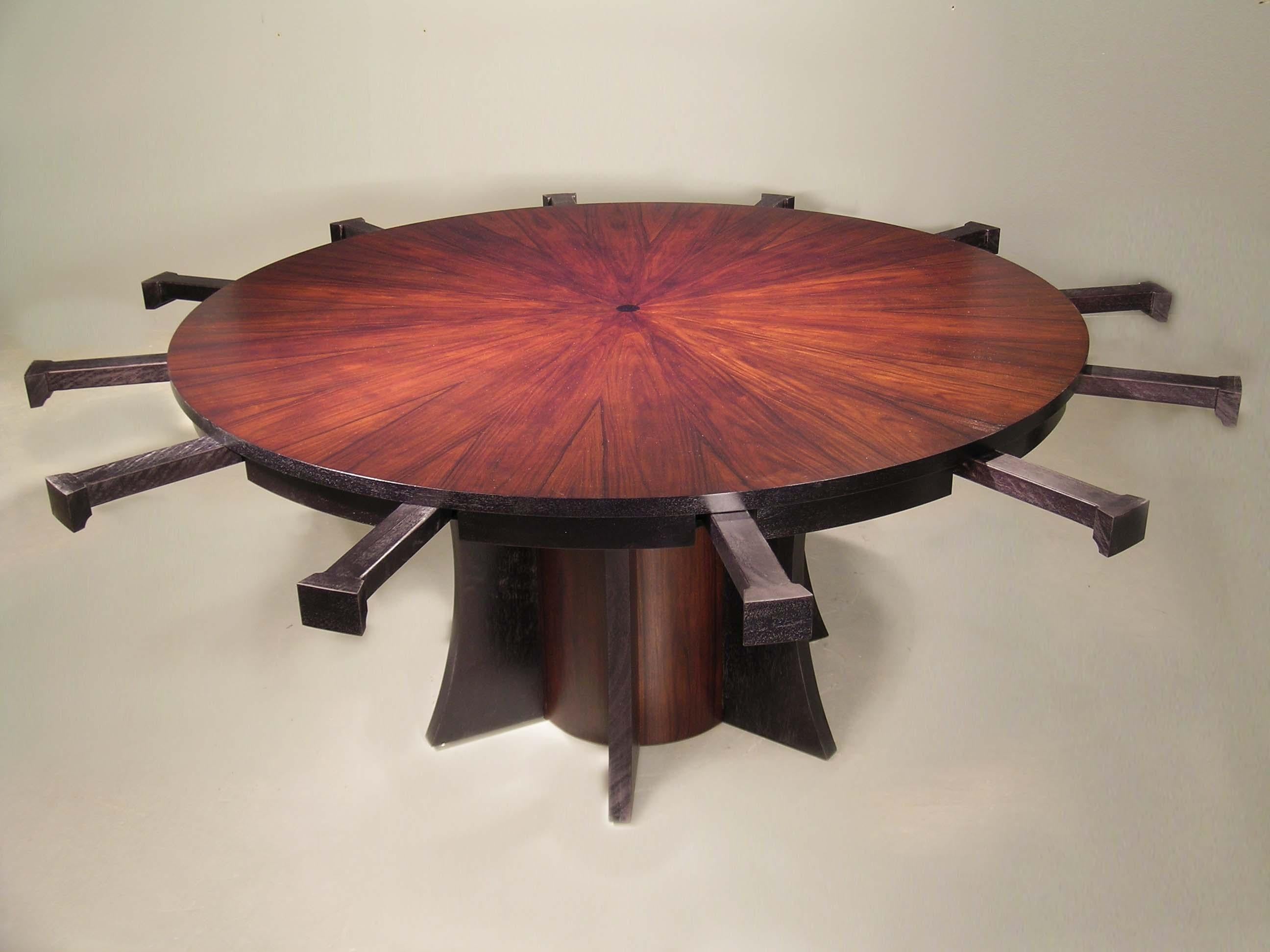 This large round dining table expands with curved leaves that rest on pull out brackets. The table top is a starburst patterned rosewood. The leaves are black mahogany. The pedestal bas is rosewood with black mahogany wings.
Without the leaves the