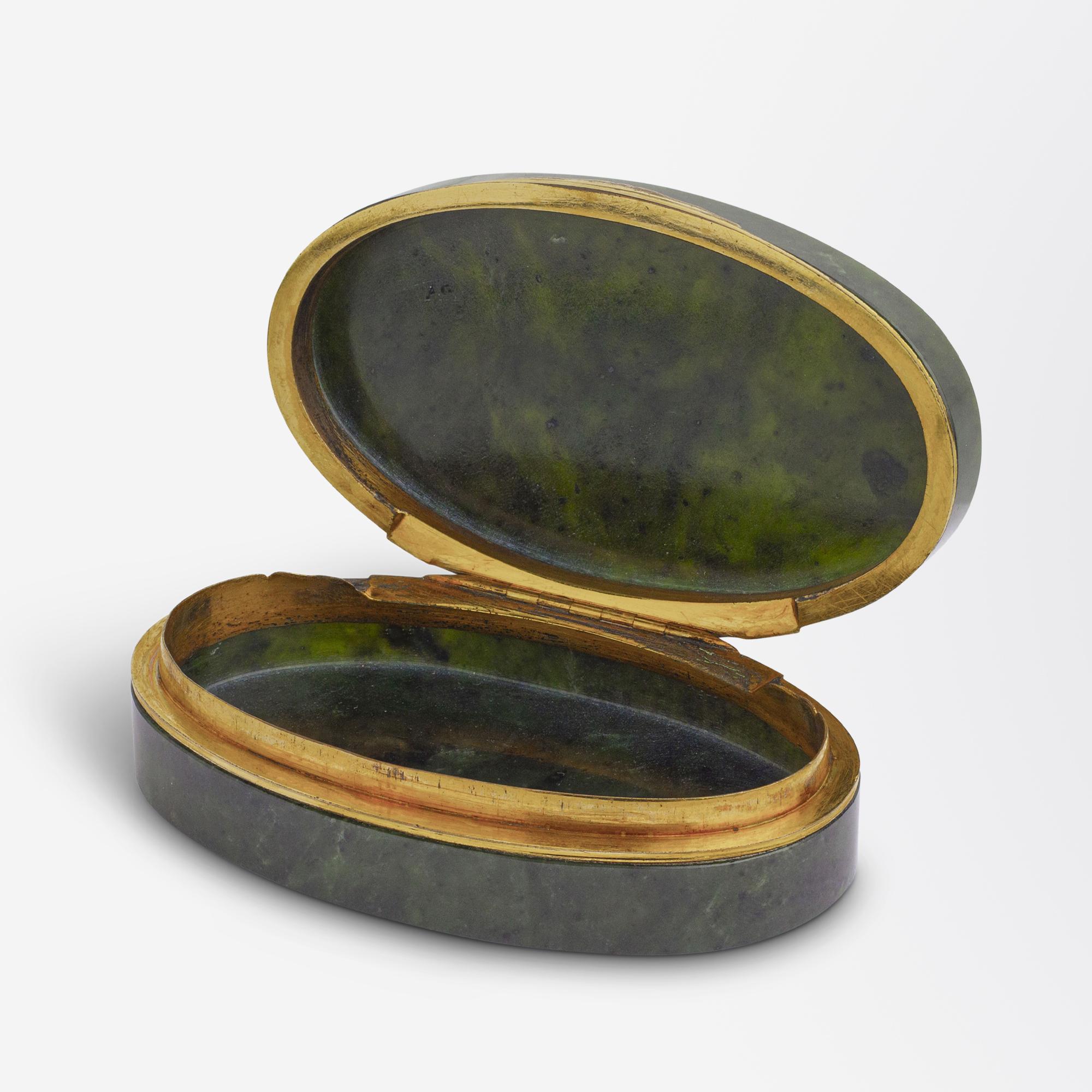 Diese Dose aus Spinatjade und vergoldetem Metall stammt aus der Zeit der Jahrhundertwende und wurde wahrscheinlich in Russland hergestellt. Die Schatulle, die in Aussehen und Haptik an Faberge erinnert, wurde wahrscheinlich am Ende der russischen