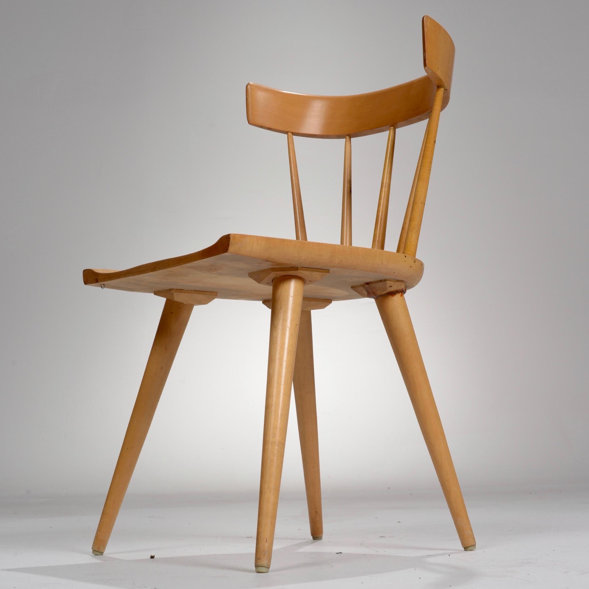 Maple spindle back dining chair from the Planner Group series designed by Paul McCobb and manufactured by Winchendon, Massachusetts. The seat rests atop four tapered legs and is inlaid with four oversize wooden screw motifs.

  