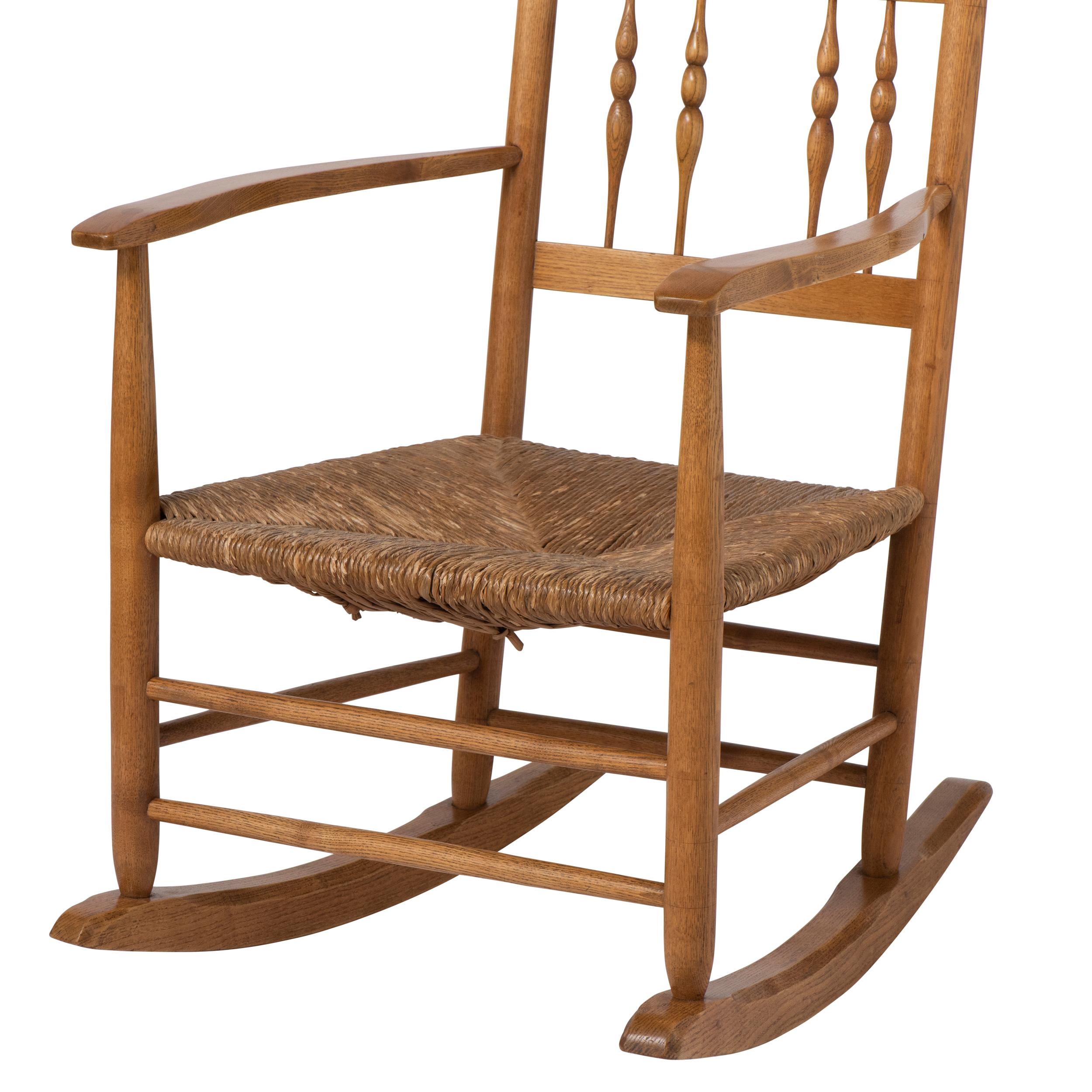 British Spindle back Rocking Chair with rush seat by Neville Neal, England circa 1920. For Sale