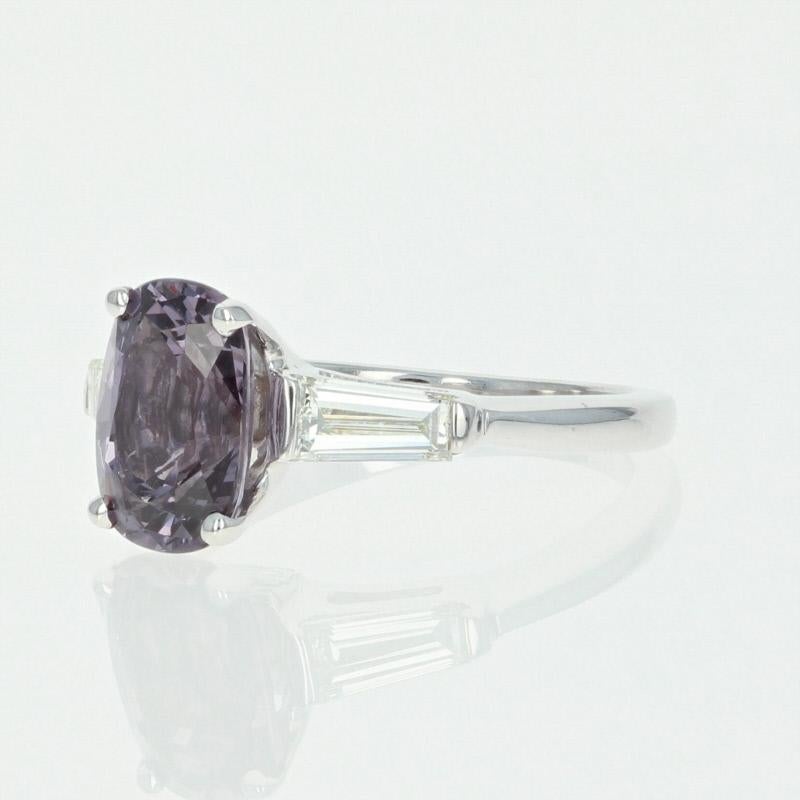 Radiant mystique defined! Composed of 14k white gold, this breathtaking ring showcases a shimmering purple spinel solitaire that is elegantly accompanied by two baguette cut diamond accents.  

This ring is a size 6, but it can be re-sized up 2