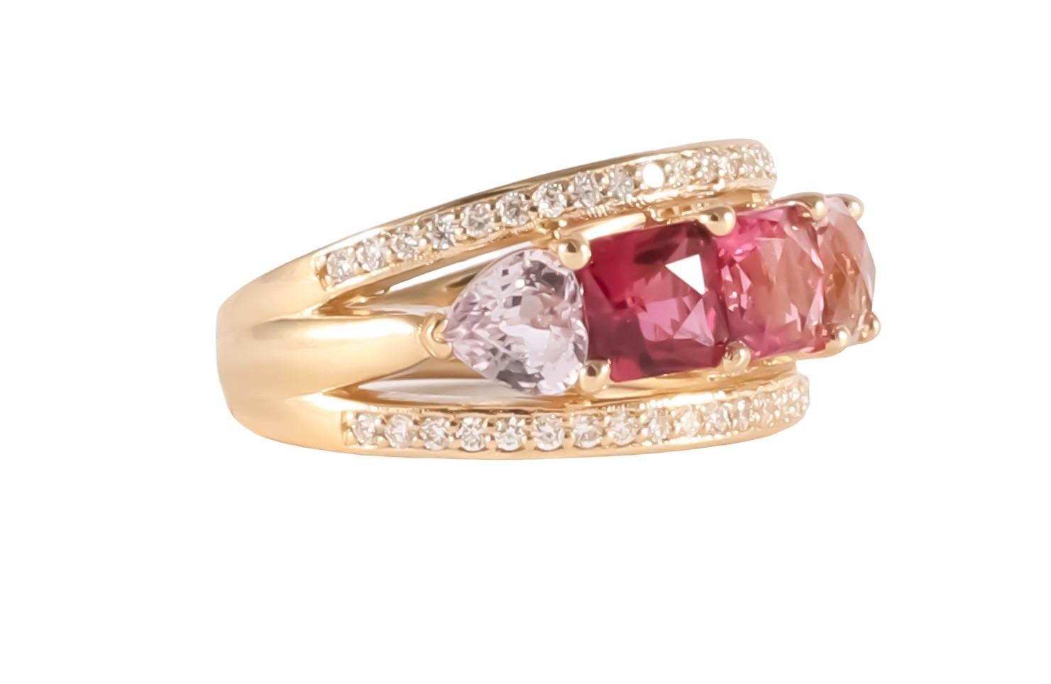 Vivid shades of red and pink spinel are set from dark to light with two heart shaped sapphires on either end and a row of round brilliant diamonds above and below the main setting. 