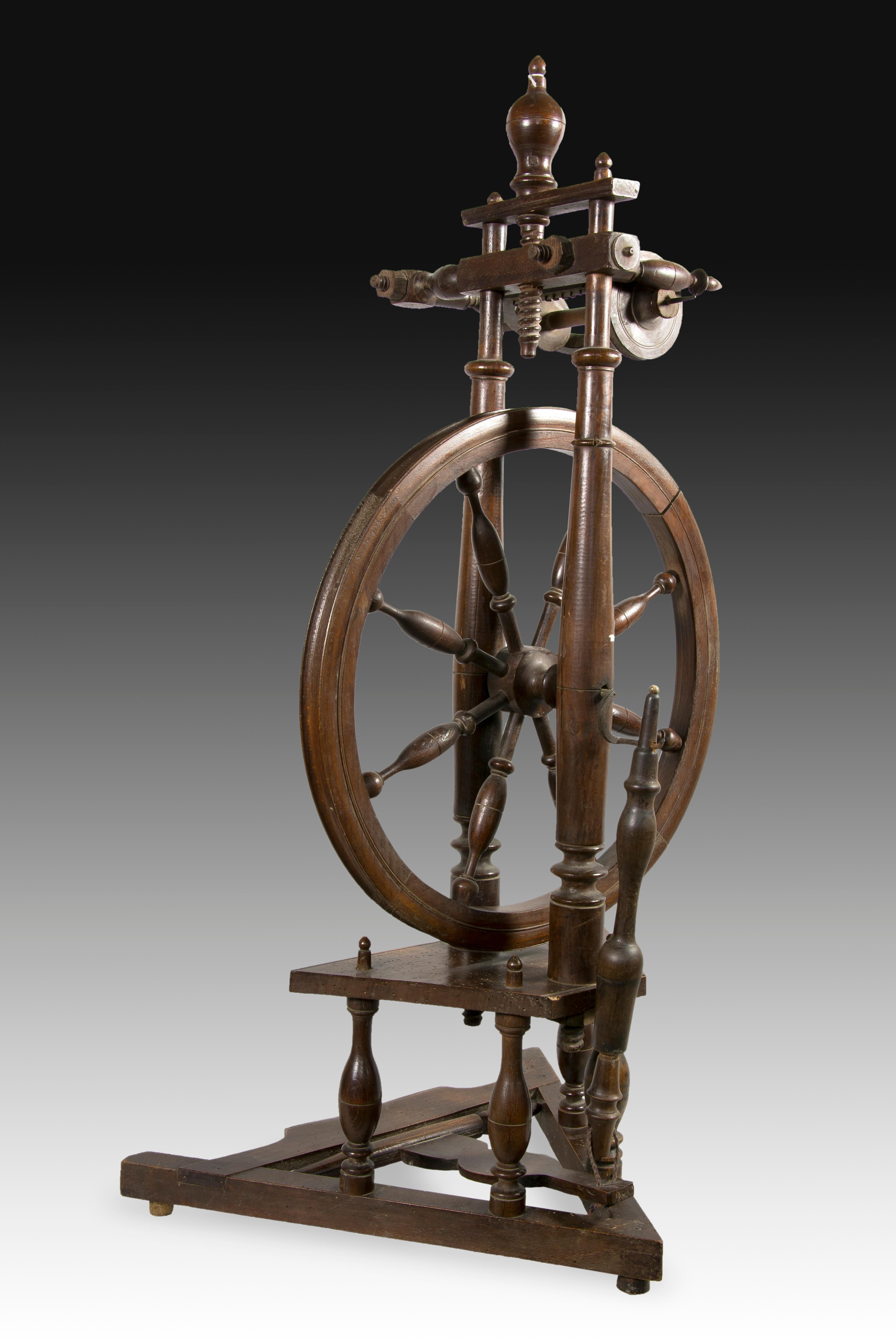 Spinning wheel. Walnut wood carved and turned. XIX century. 
 Vertical spinning wheel made of carved walnut wood decorated with fine lines in certain areas and the use of balustraded pieces where these have been considered necessary. Compare, for