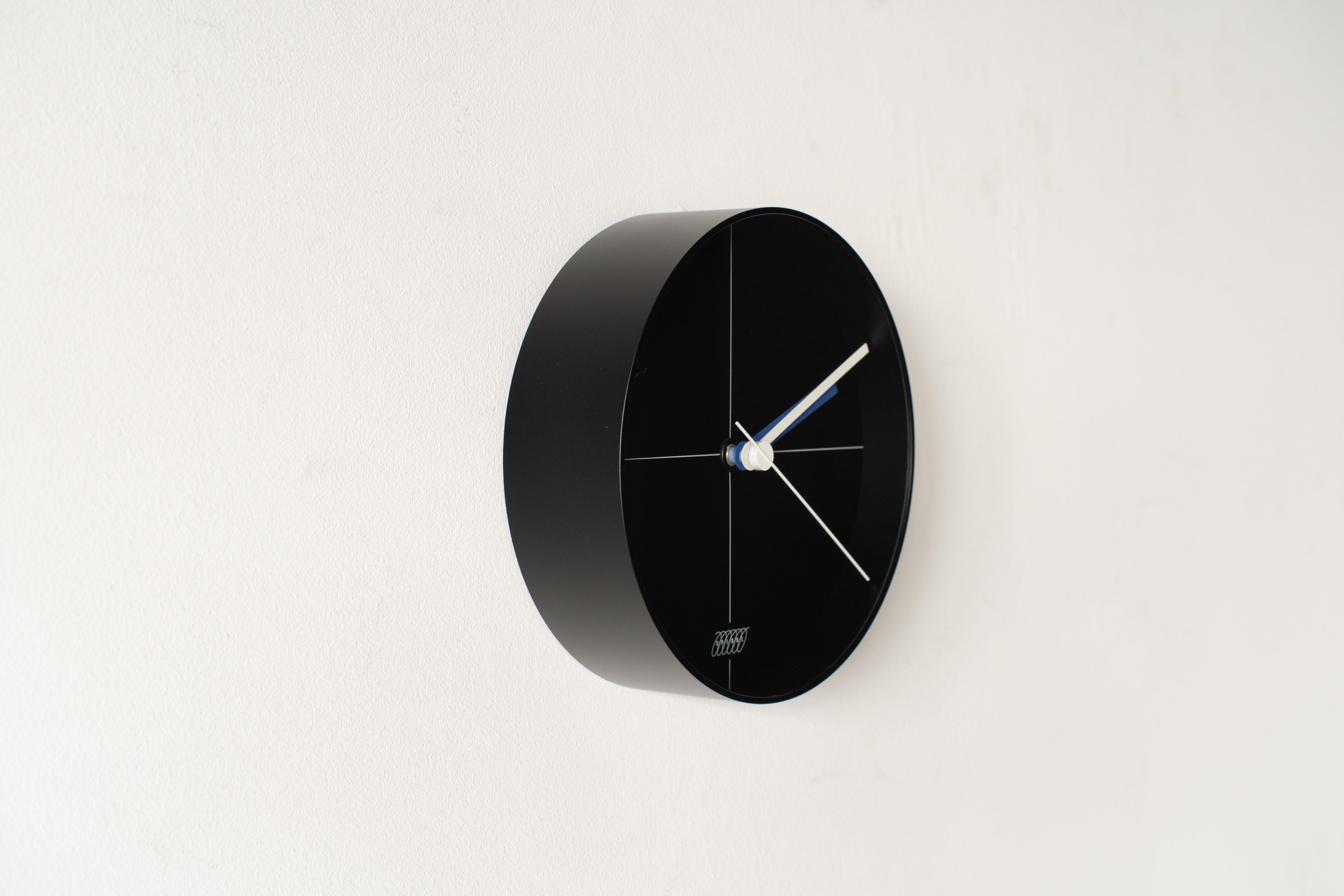 Horloge spirale B #3 corps noir conçu par Shiro Kuramata. Le cadran se trouve à l'intérieur d'un abat-jour arrondi à bord acrylique.
 