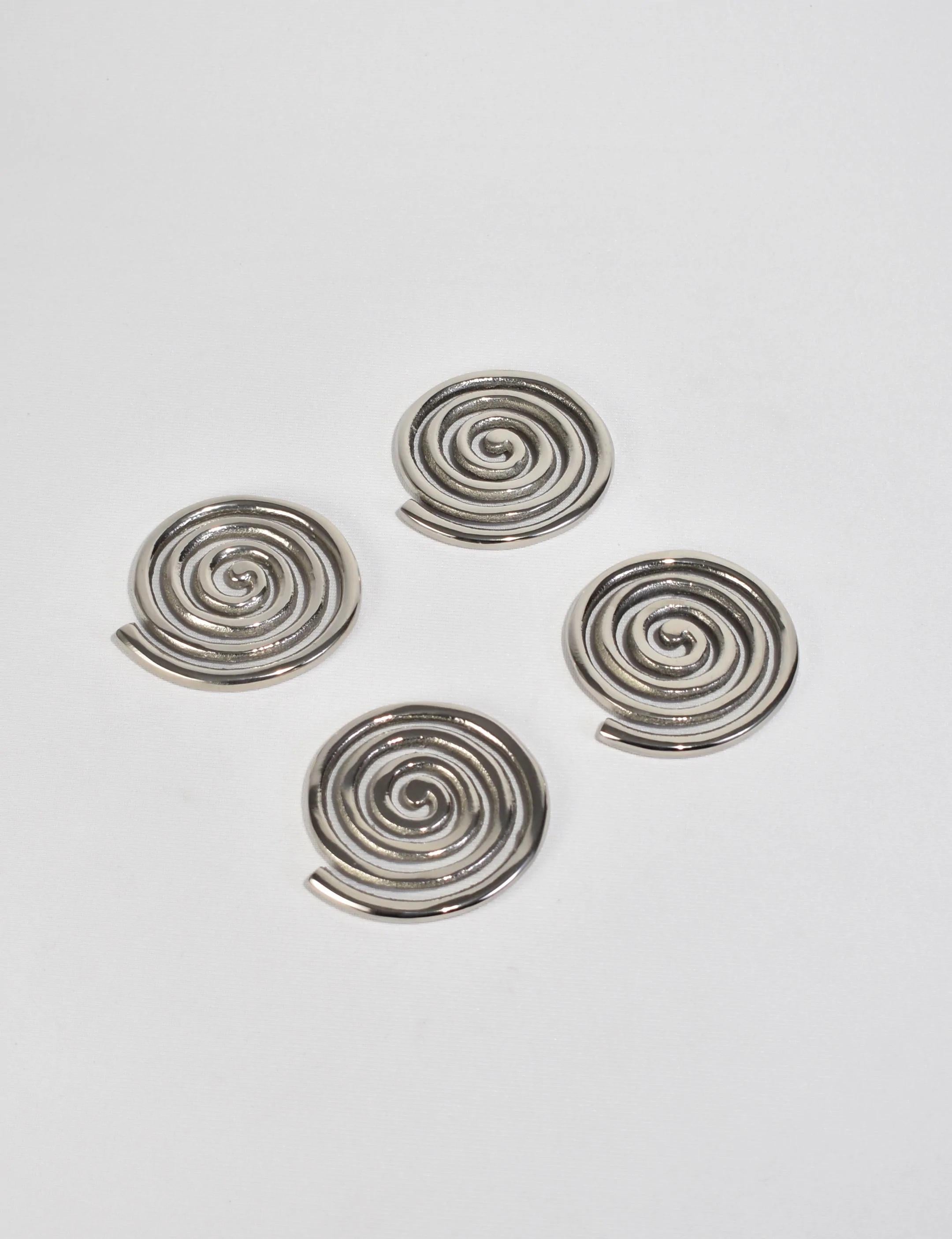 A set of four sand-cast aluminum spiral coasters plated in nickel. These coasters will add joyful personality to your table-scape while protecting whatever surface lies beneath.

