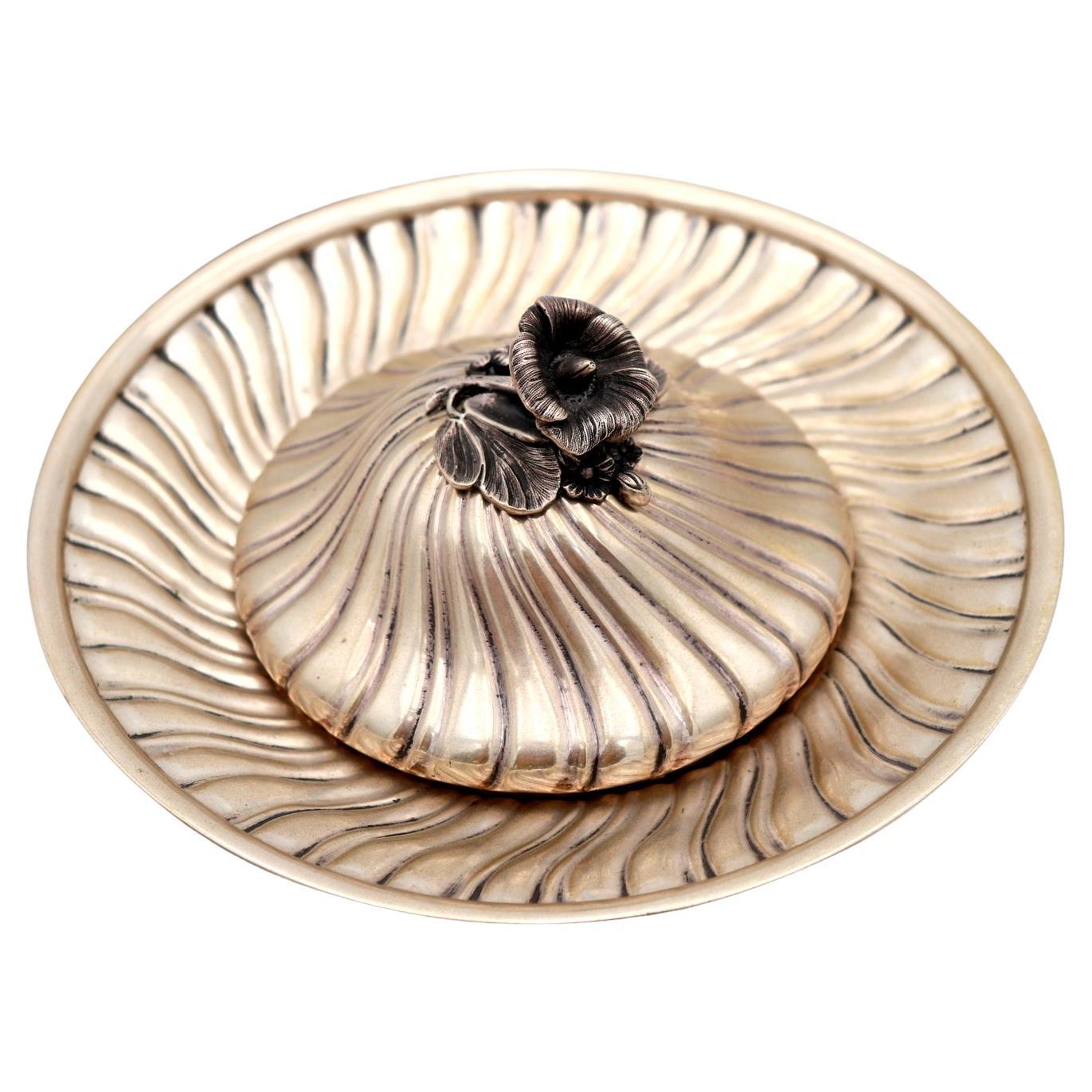 Spiral silver cheese dish w/ a flower-shaped knob on the lid 
embossed details