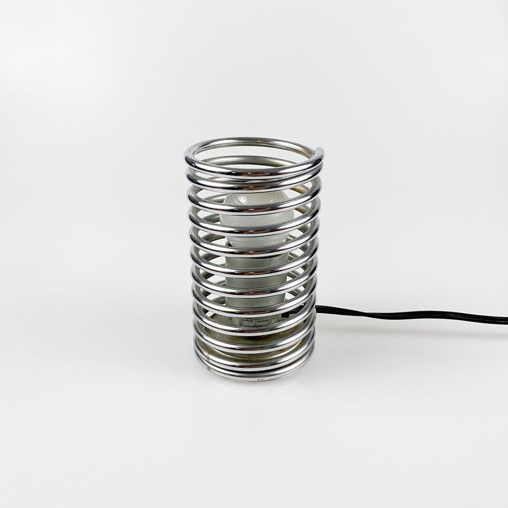 Spiral table lamp, 1970's 

Made of steel. 

E27 socket bulb, European plug.

Measurements: 8 cm. of diameter 14 cm. height.