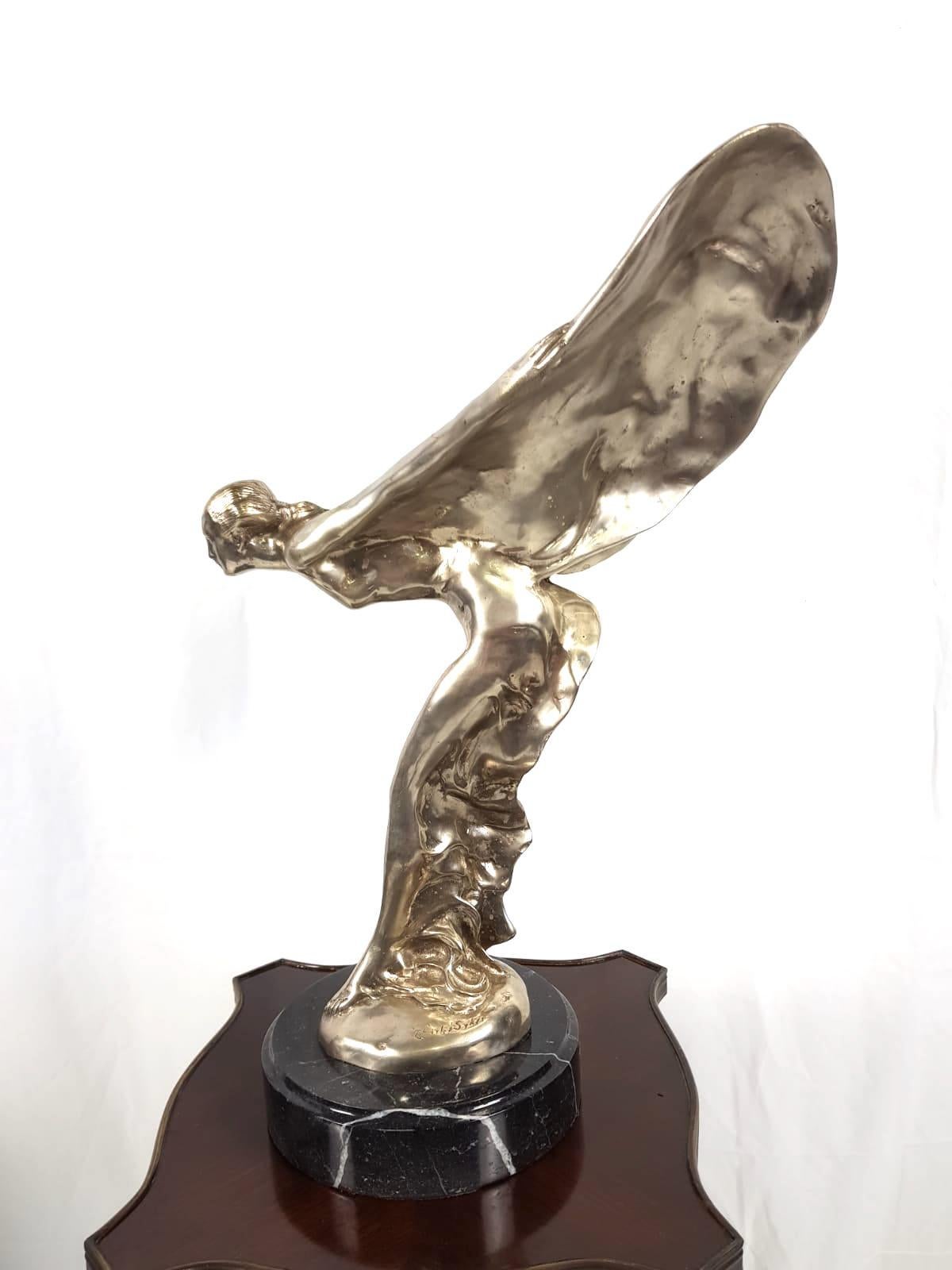 A 20th Century “Spirit of Ecstasy” silver plated statue on marble platform
Signed by artist, Charles Sykes 

The spirit of Ecstasy is the bonnet ornament on Rolls-Royce cars. It is in the form of a woman leaning forwards with her arms outstretched